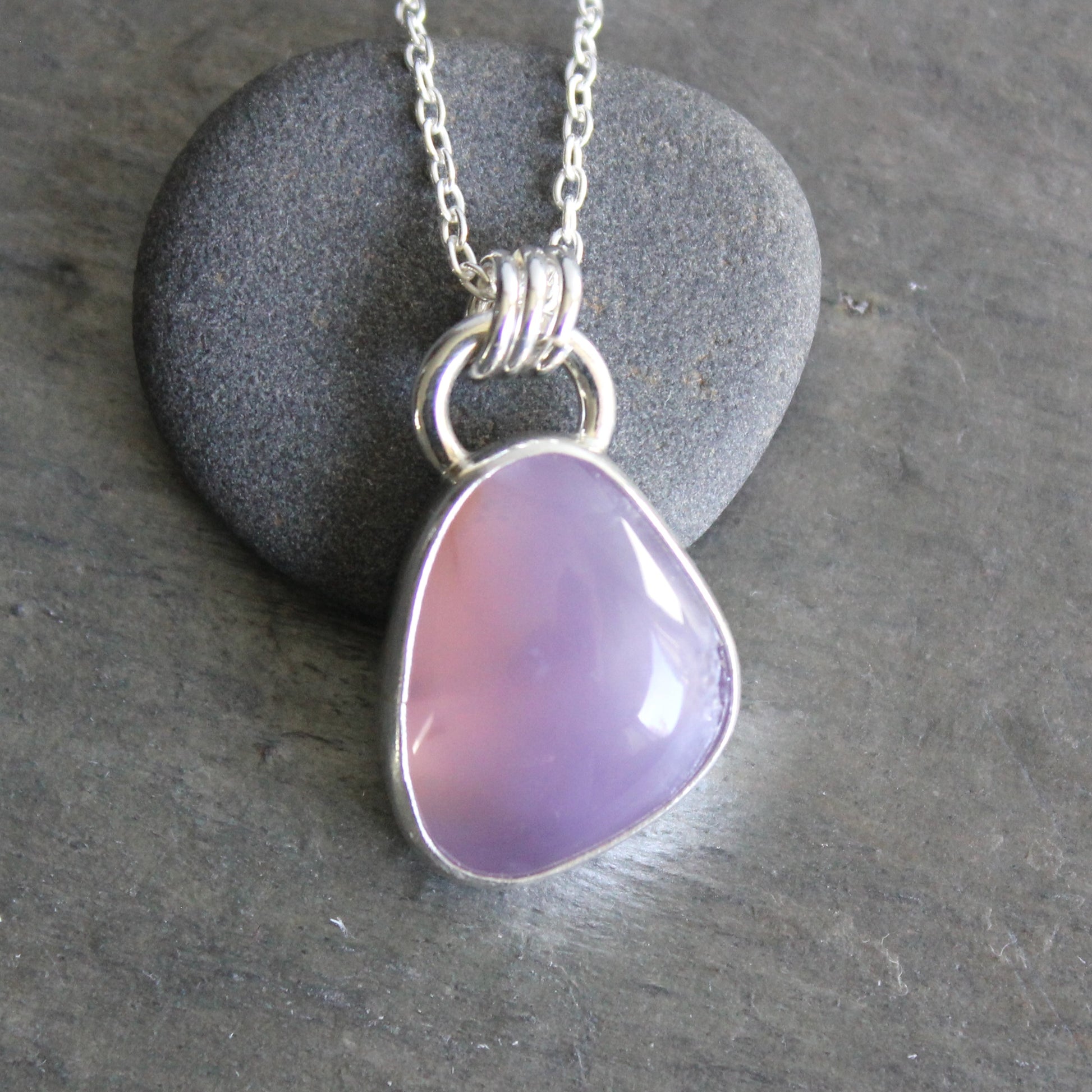 Necklace with a purple holley blue agate pendant on a gray stone surface