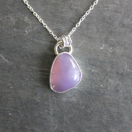 Necklace with a purple holley blue agate pendant on a gray stone surface