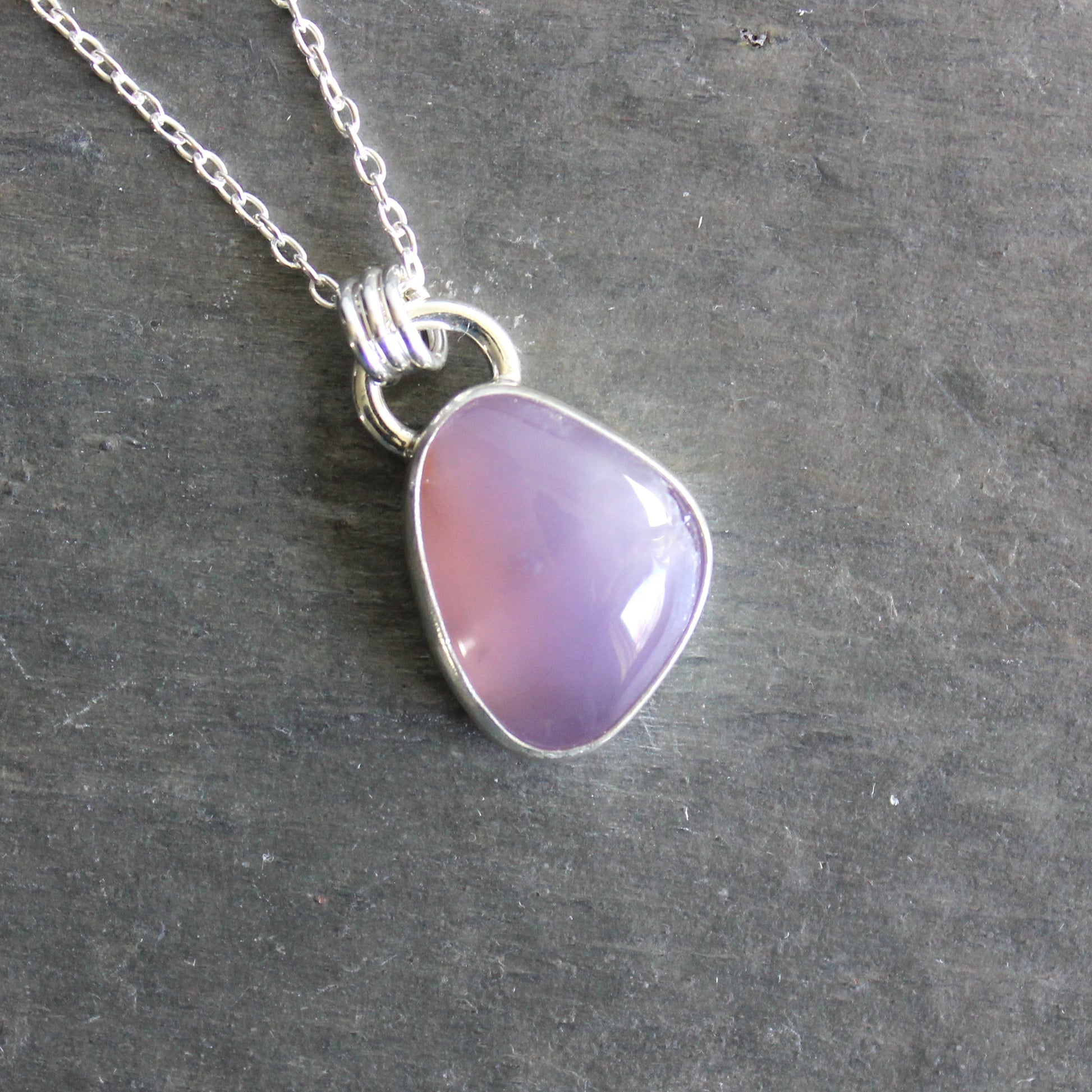 Necklace with a purple holley blue agate pendant on a gray stone surface