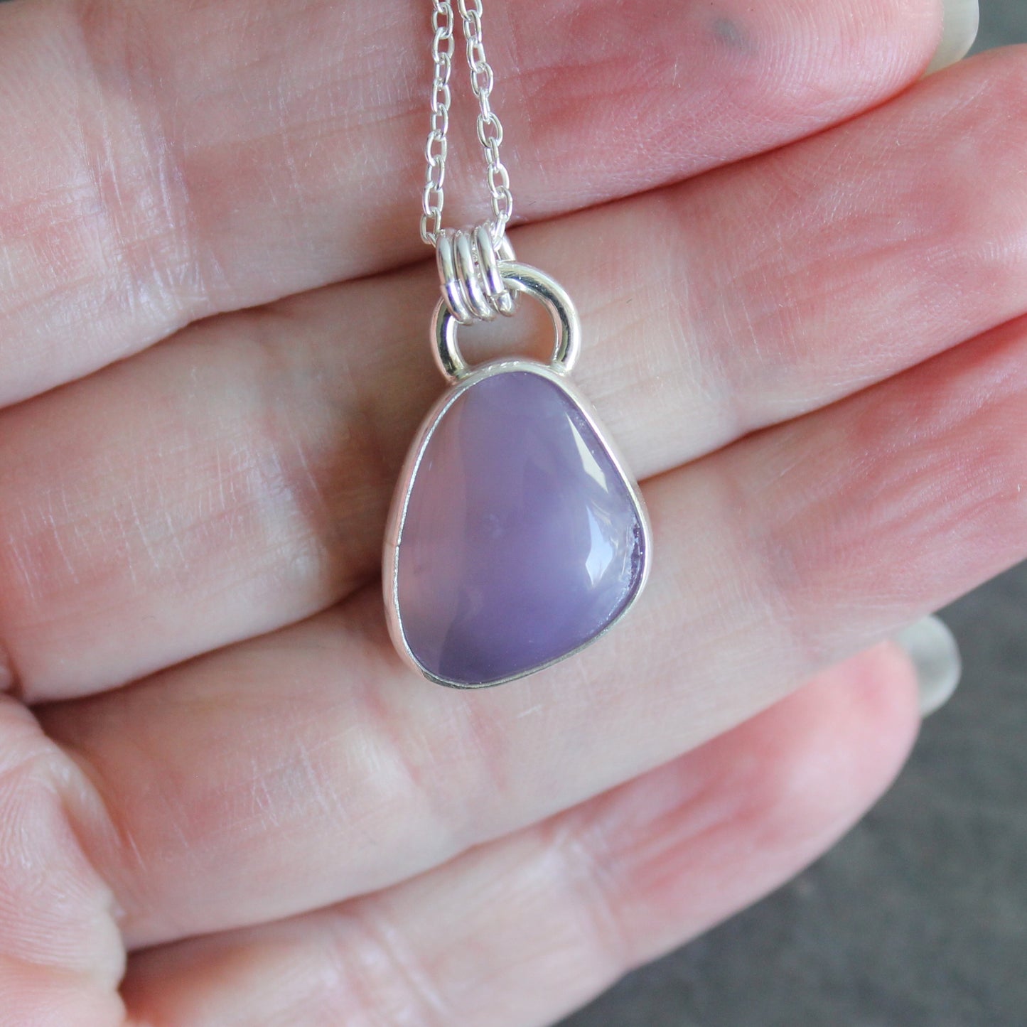 Necklace with a purple holley blue agate pendant on a hand