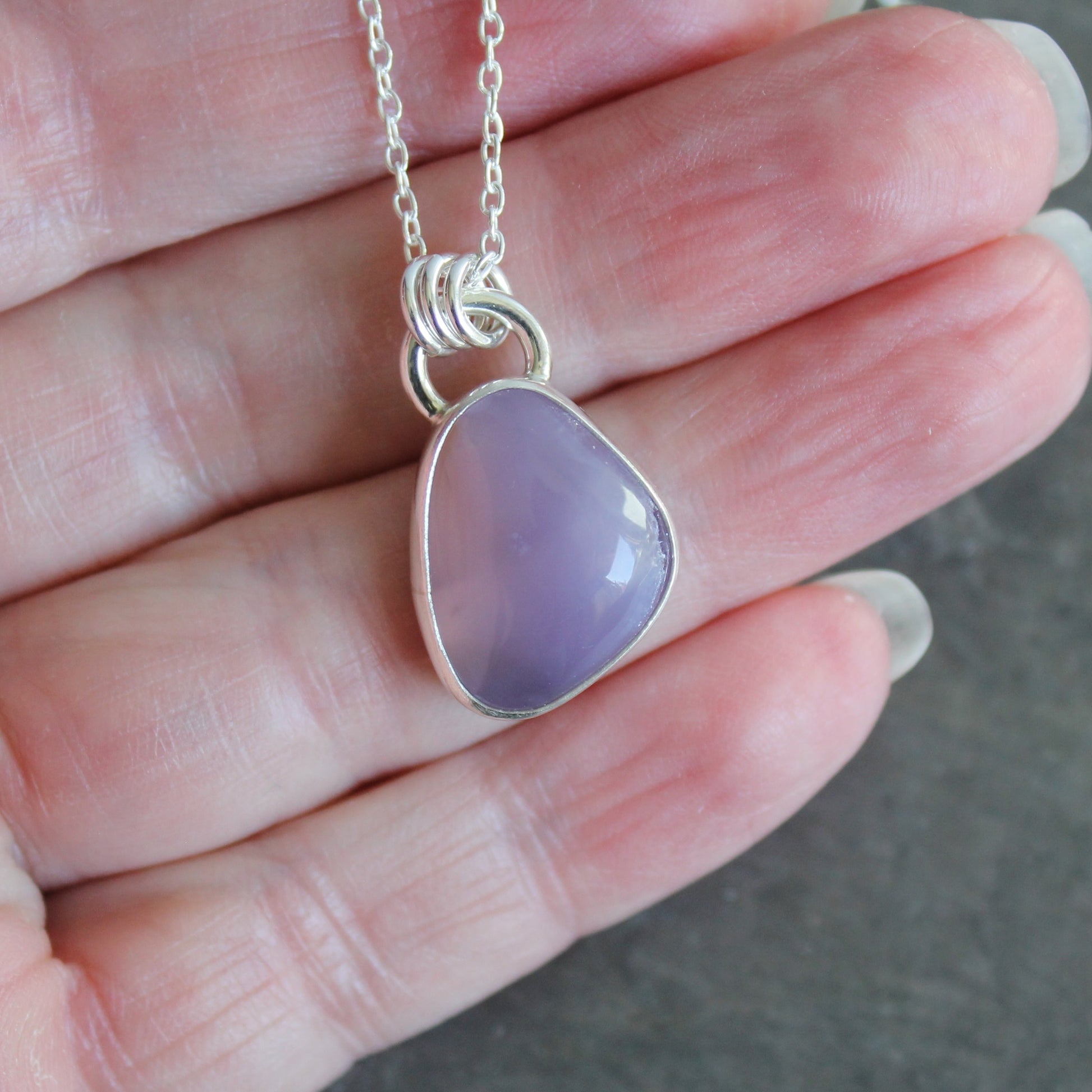 Necklace with a purple holley blue agate pendant on a hand
