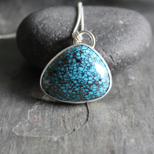 This is a huge triangular spider web turquoise with a pyrite matrix that is set in a fine and sterling silver bezel setting.  The stone measures approxximately 1" x 1 1/2". 