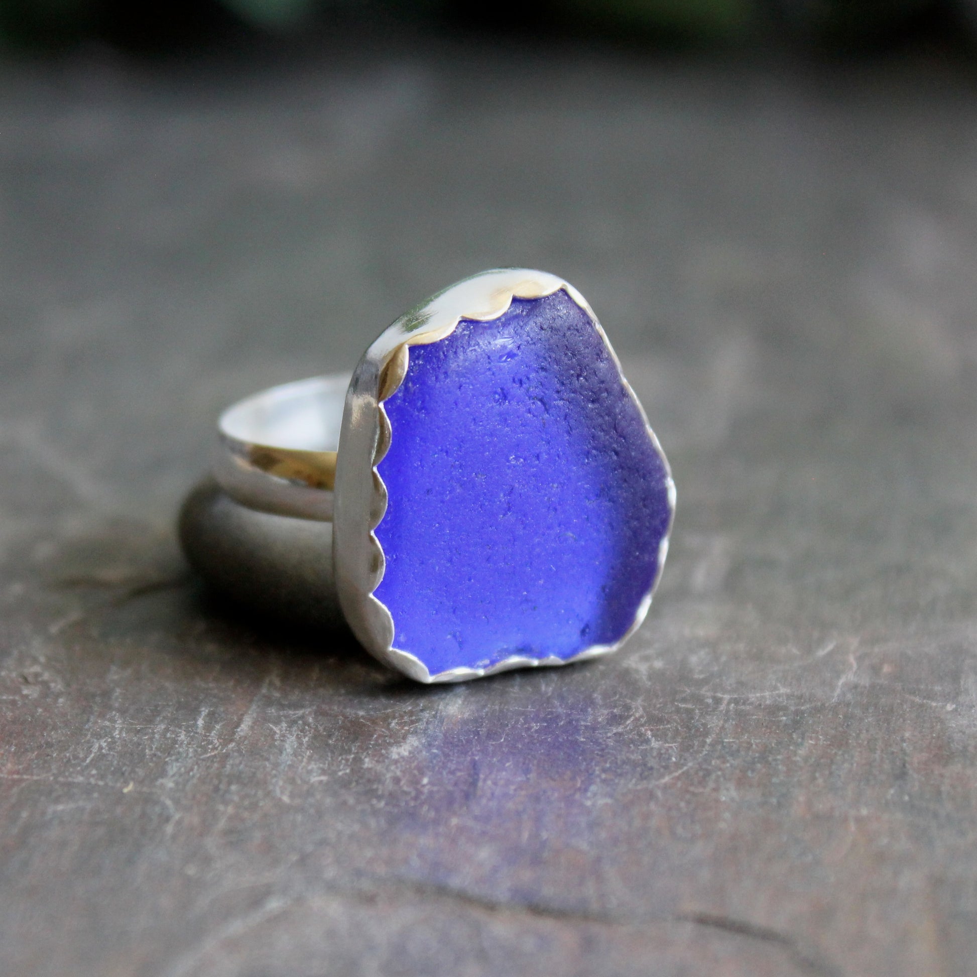Blue sea glass ring with silver band on a dark surface