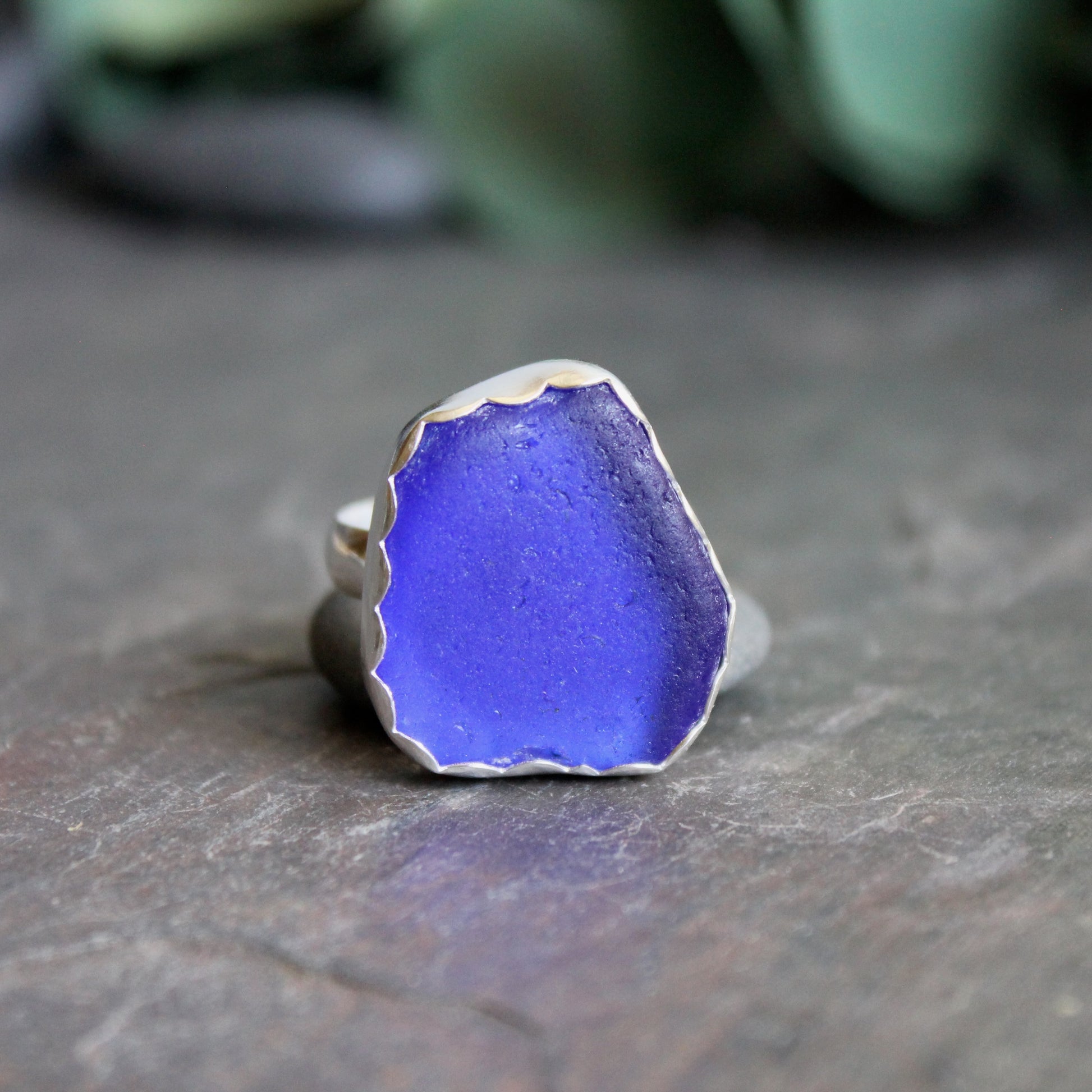 Blue sea glass ring with silver band on a dark surface