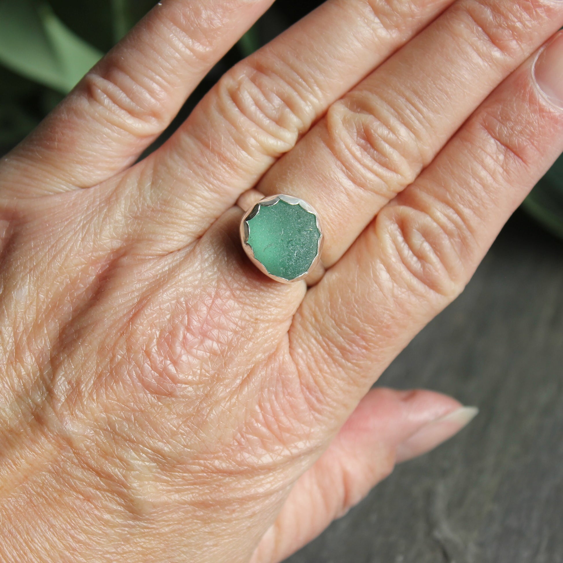 This ring has a chunky piece of teal green sea glass that is set in a fine and sterling silver scalloped bezel setting on a sturdy silver band.  Size 8 1/2