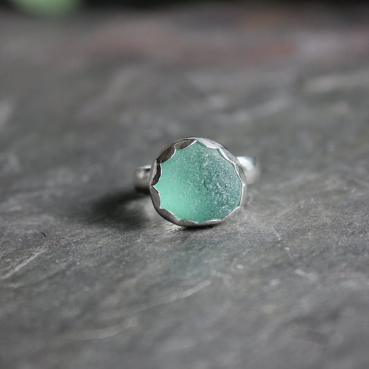 This ring has a chunky piece of teal green sea glass that is set in a fine and sterling silver scalloped bezel setting on a sturdy silver band.  Size 8 1/2