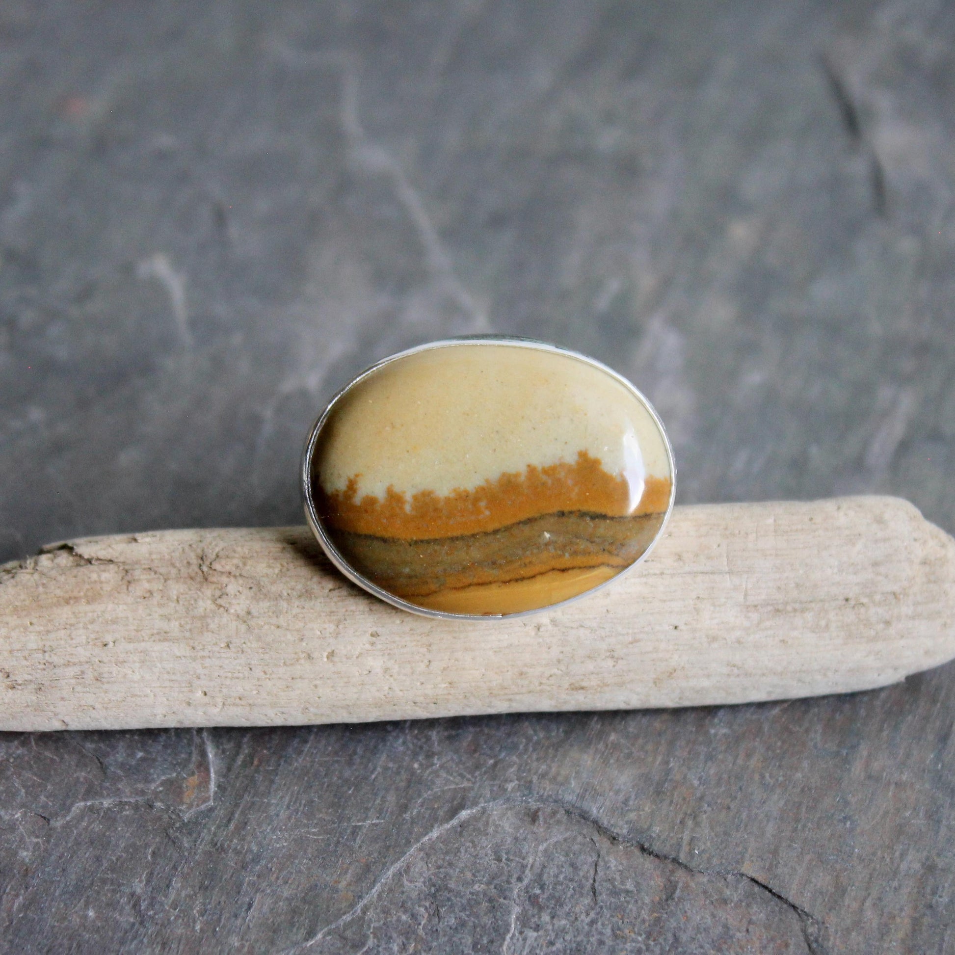 This ring has a large oval Owyhee picture jasper cabochon set in a fine and sterling silver bezel setting on a sturdy hammered band. Size 9 1/4