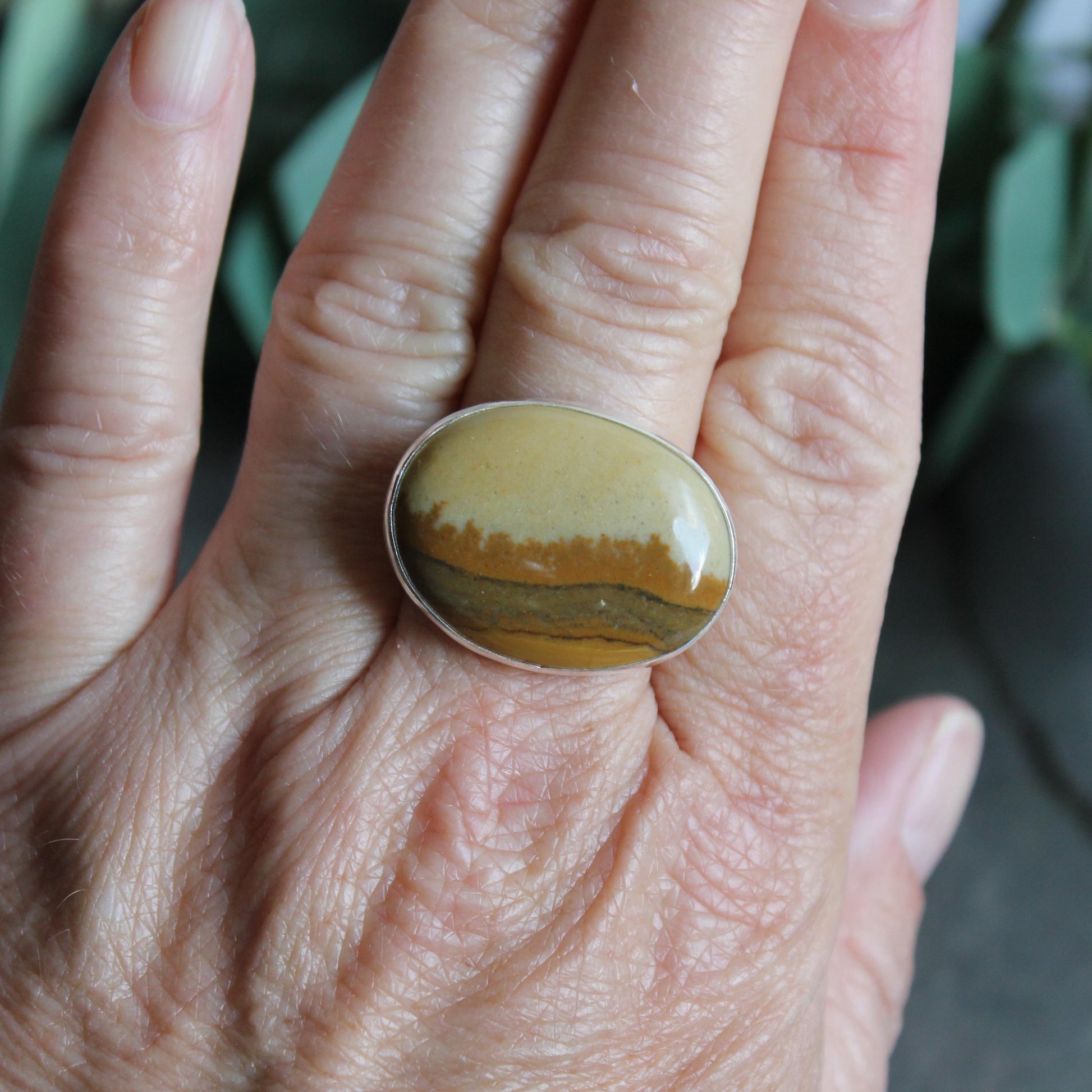 This ring has a large oval Owyhee picture jasper cabochon set in a fine and sterling silver bezel setting on a sturdy hammered band. Size 9 1/4
