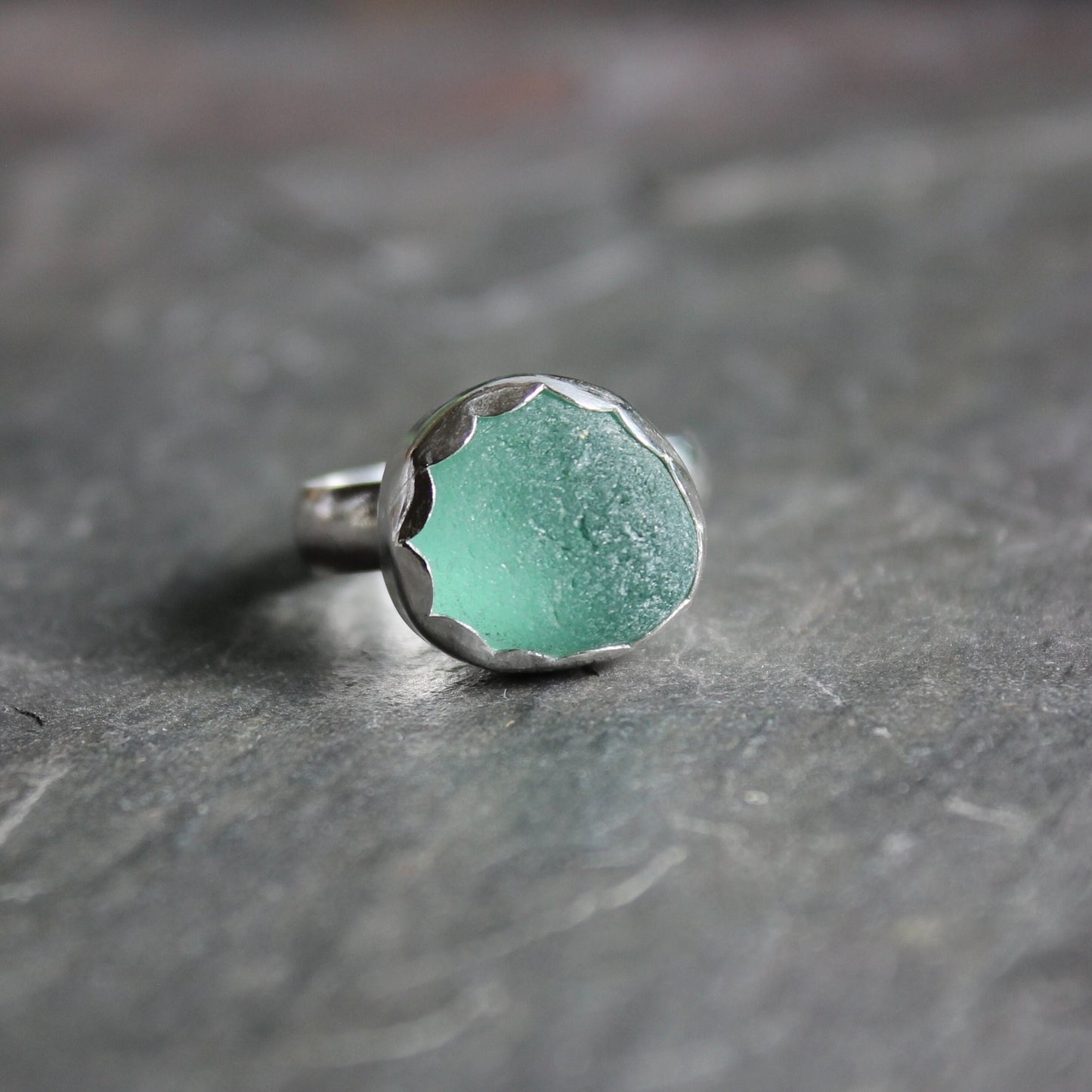 This ring has a chunky piece of teal green sea glass that is set in a fine and sterling silver scalloped bezel setting on a sturdy silver band.  Size 8 1/2