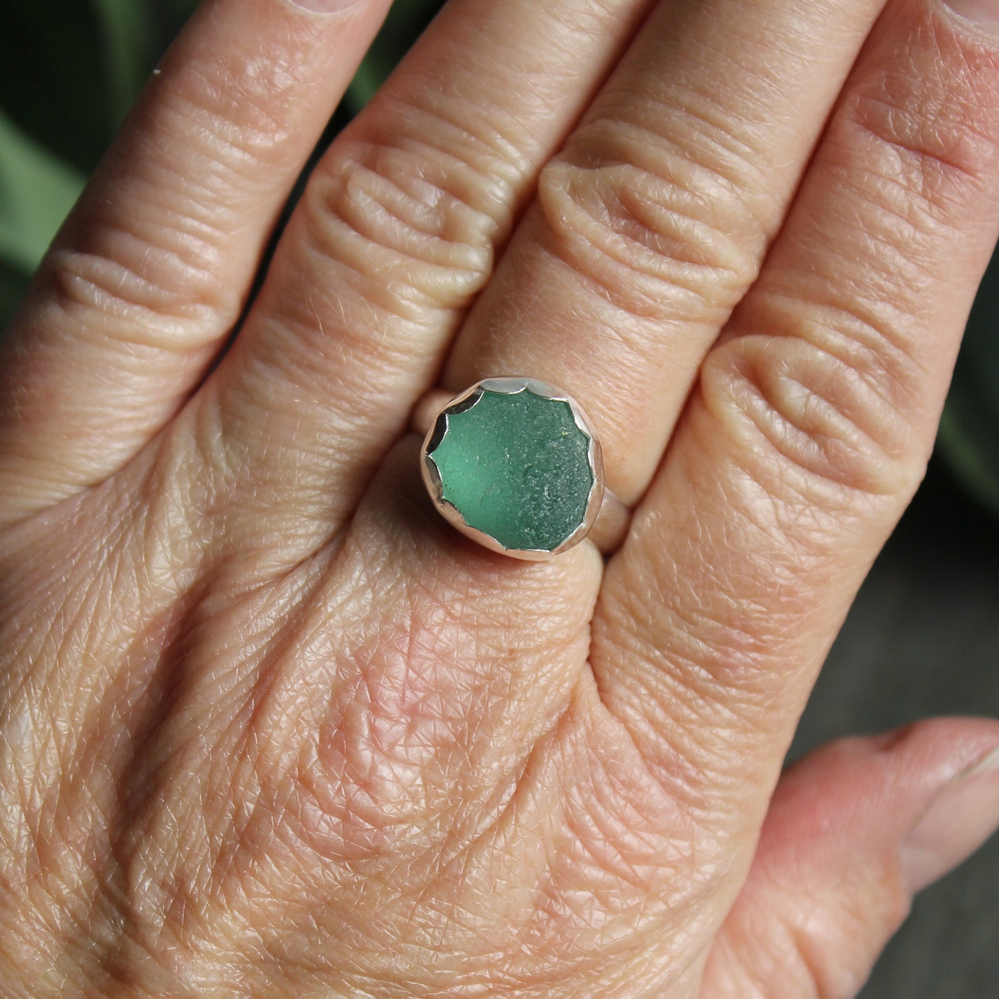 This ring has a chunky piece of teal green sea glass that is set in a fine and sterling silver scalloped bezel setting on a sturdy silver band.  Size 8 1/2