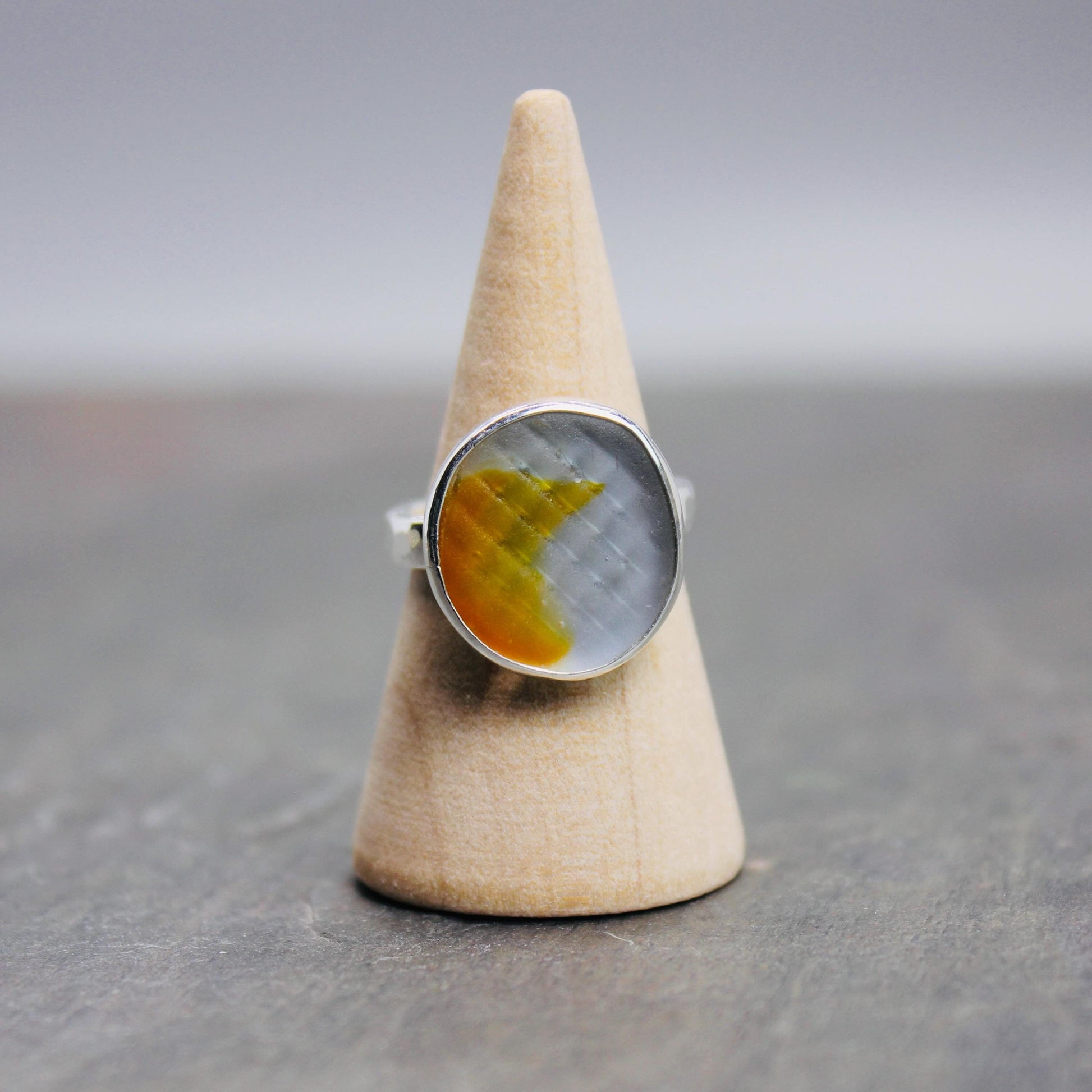 This unique ring has a rare aqua and orange Japanese Ohajiki sea glass marble set in a fine and sterling silver bezel setting on a sturdy silver band. Handmade by Barb Macy in Corvallis, OR.
