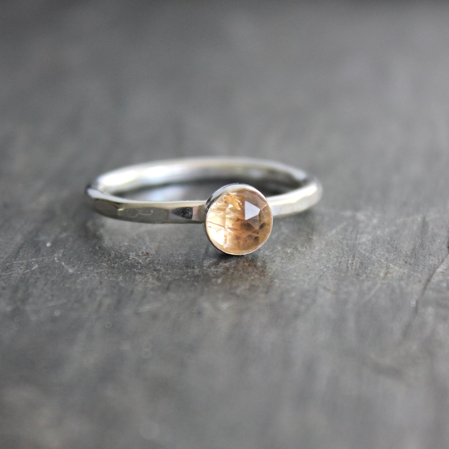 Silver ring with an imperial topaz on a gray surface