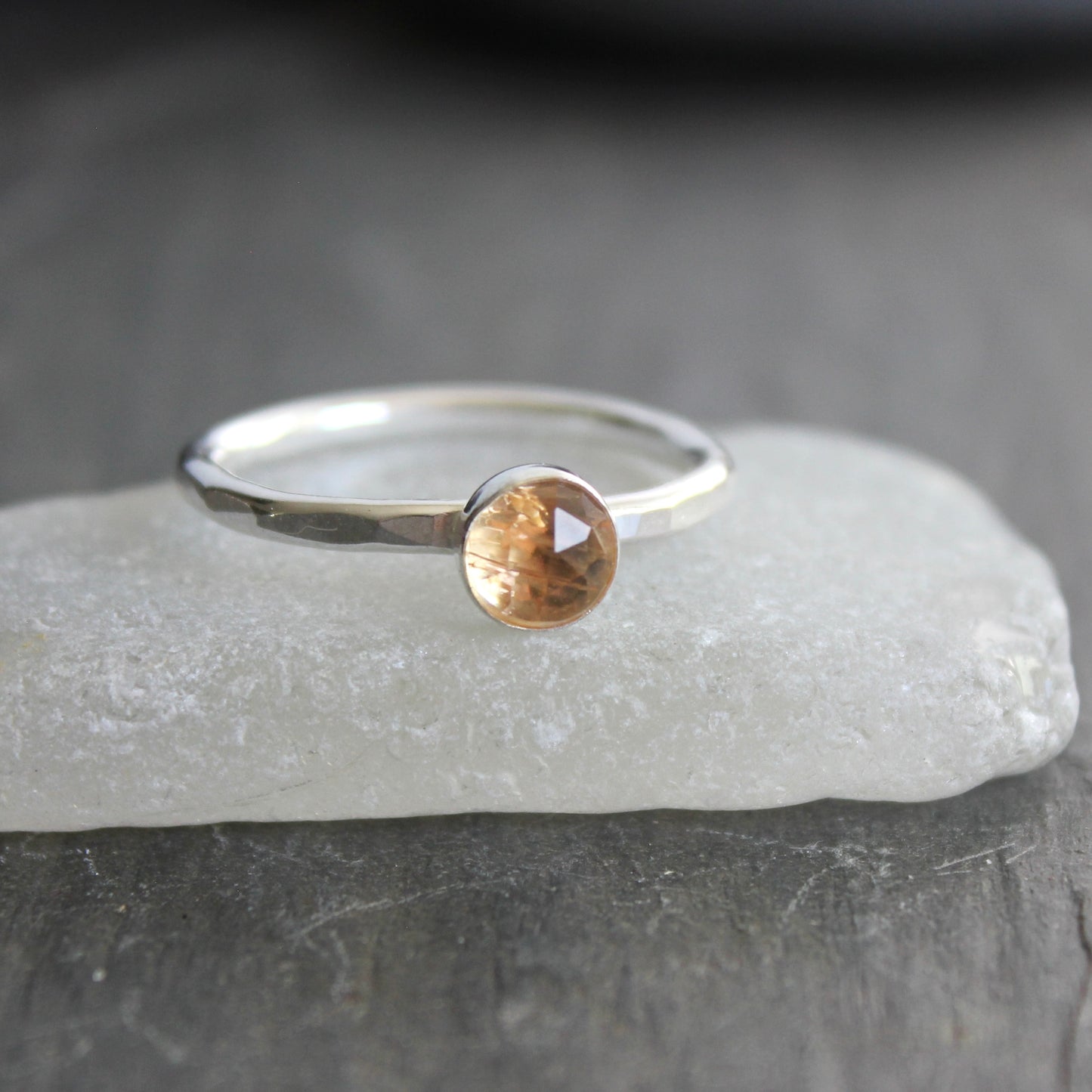 Silver ring with an imperial topaz on a gray surface