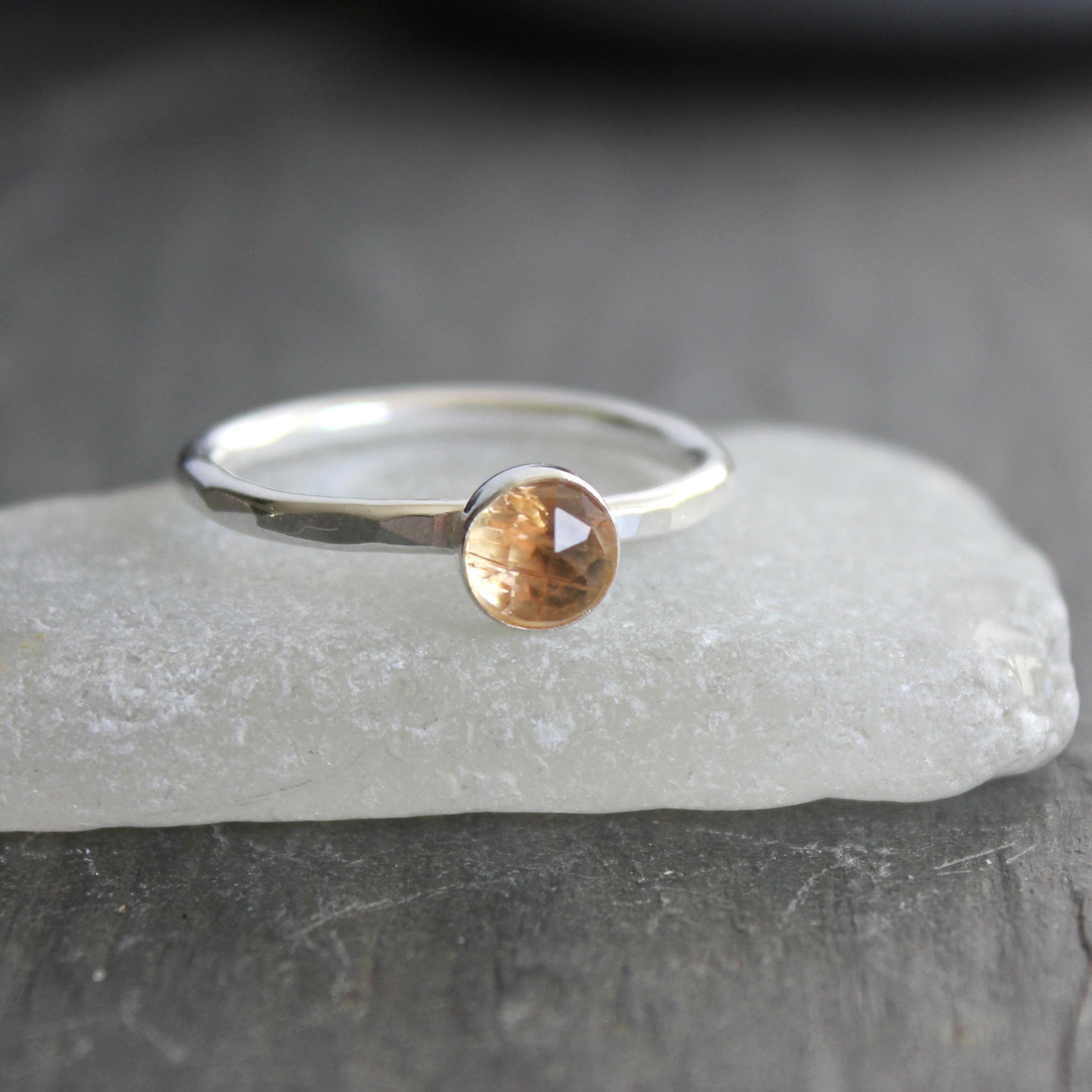 Silver ring with an imperial topaz on a gray surface
