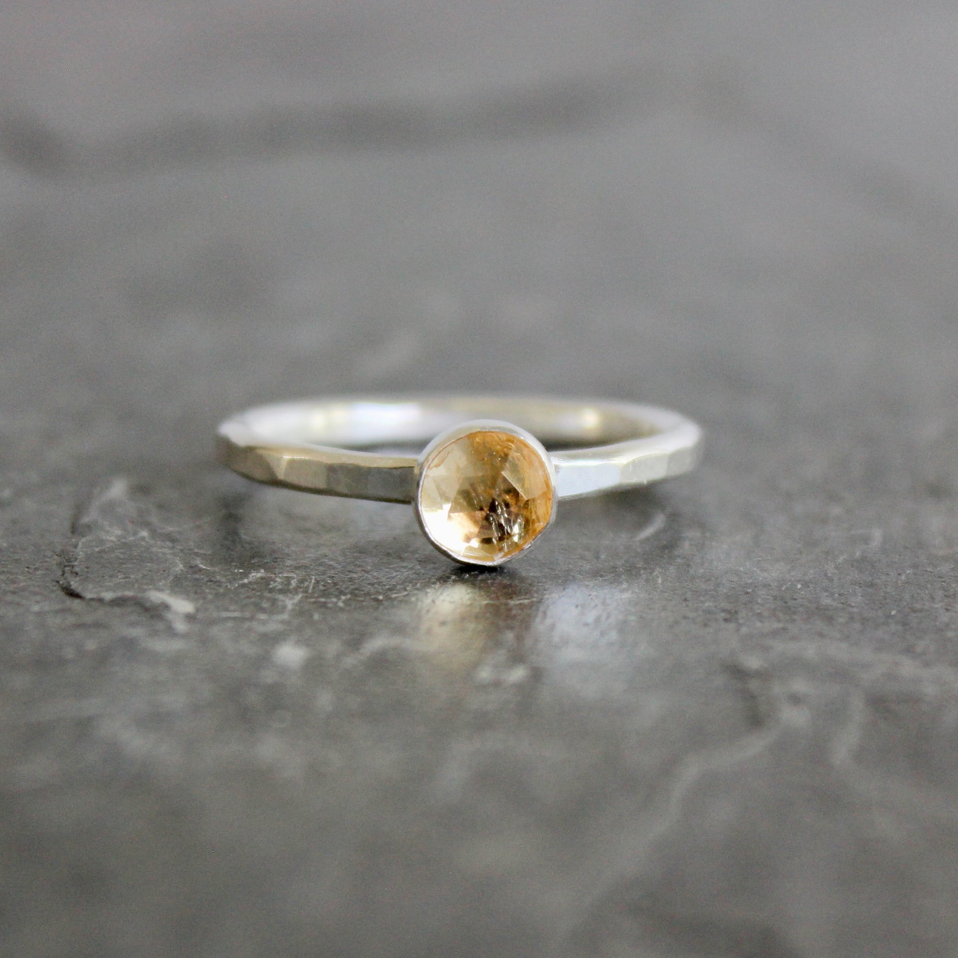 Silver ring with an imperial topaz on a gray surface