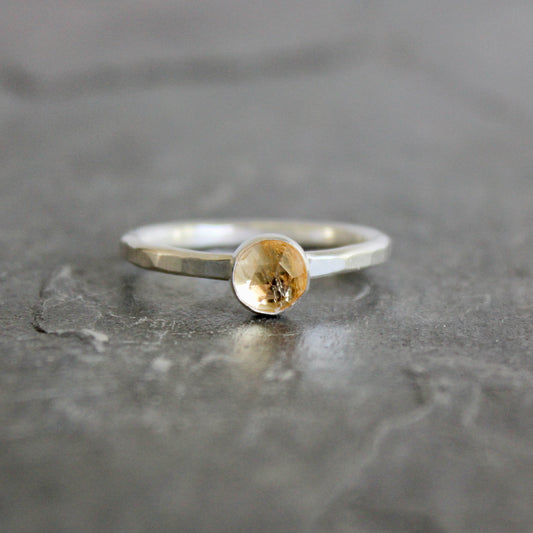 Silver ring with an imperial topaz on a gray surface