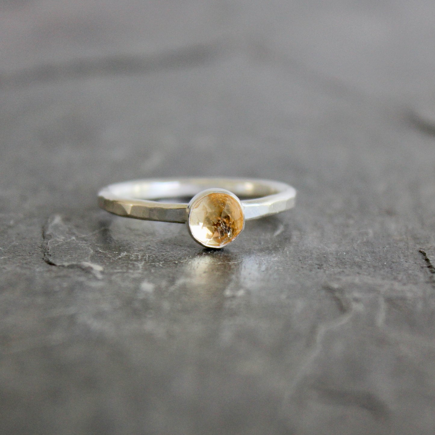 Silver ring with an imperial topaz on a gray surface