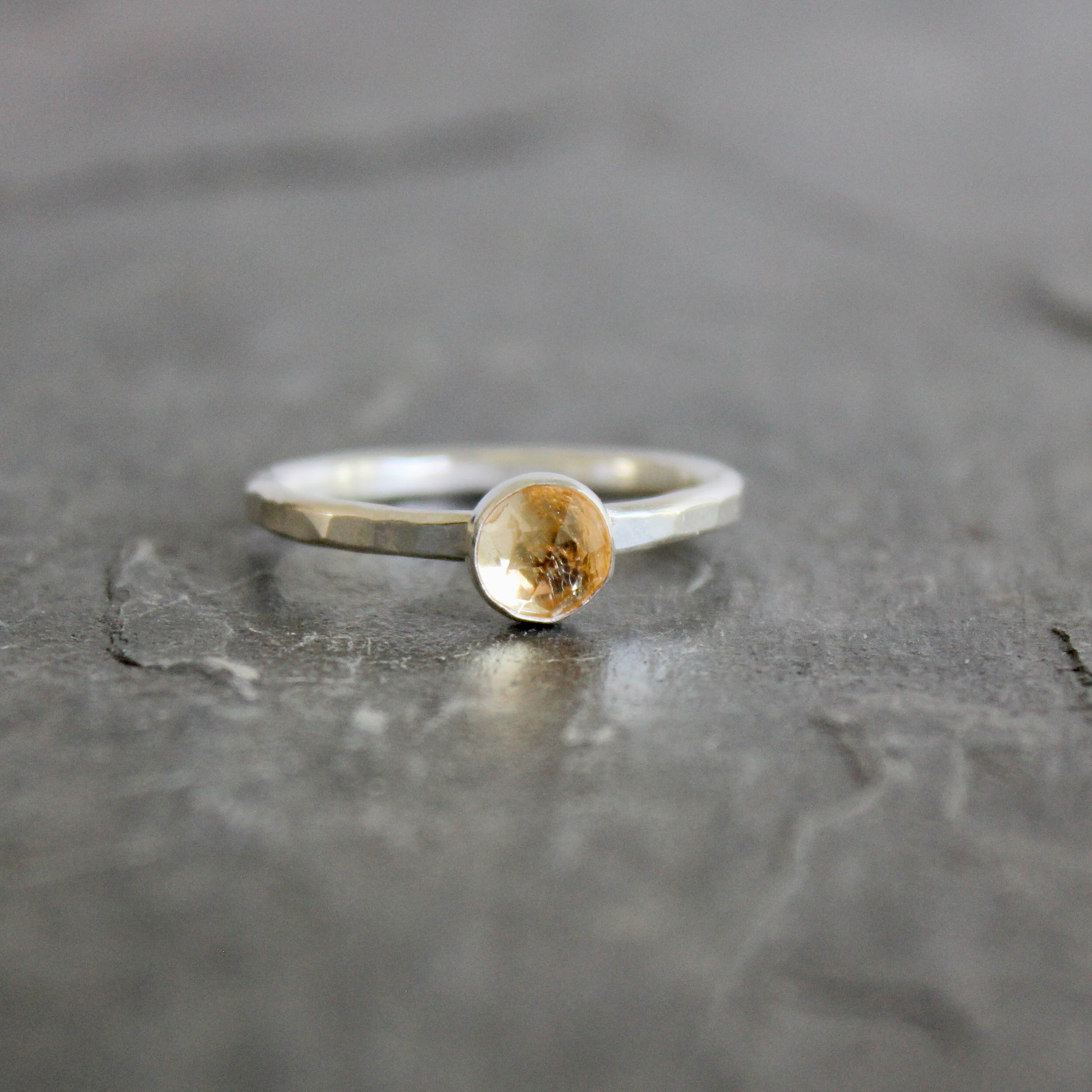Silver ring with an imperial topaz on a gray surface