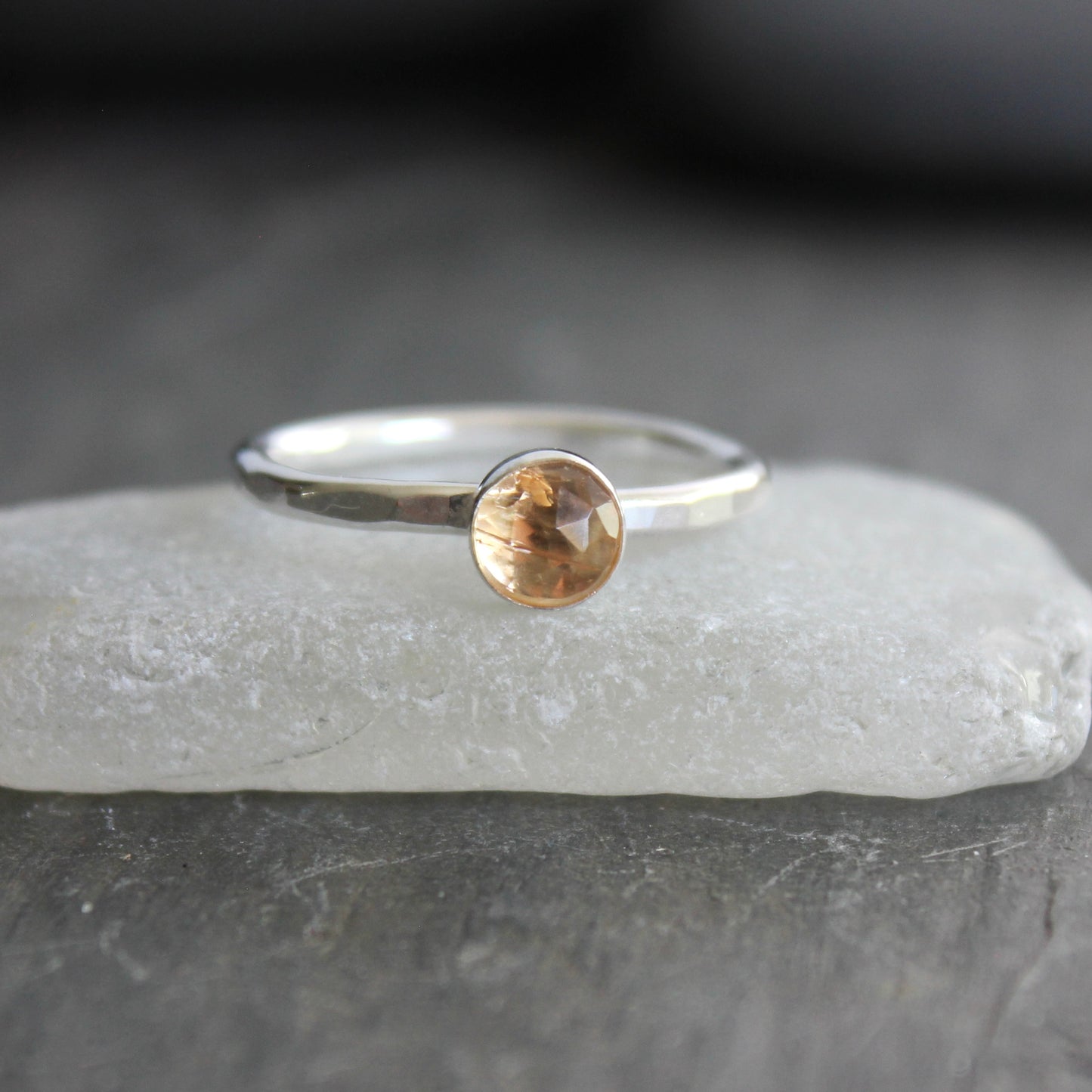 Silver ring with an imperial topaz on a gray surface