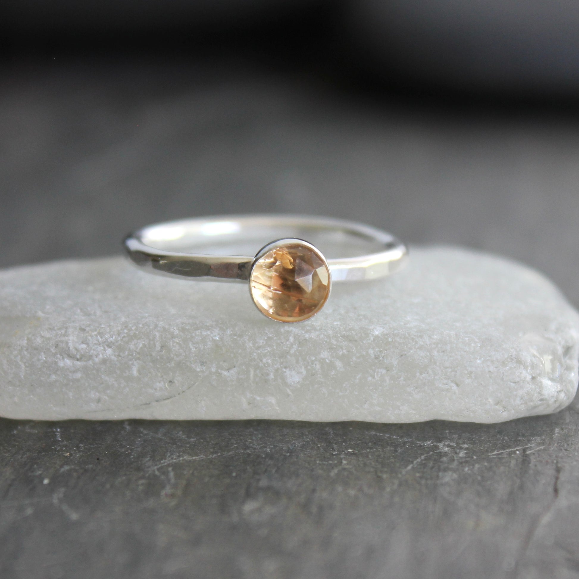 Silver ring with an imperial topaz on a gray surface