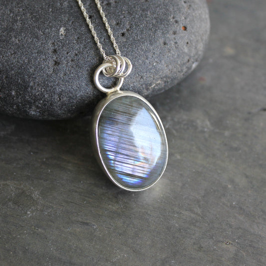 Silver pendant with a blue gemstone on a dark stone surface
