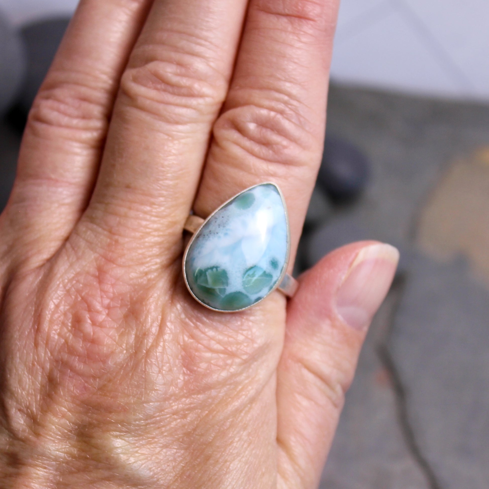 Teardrop-shaped larimar ring on a hand