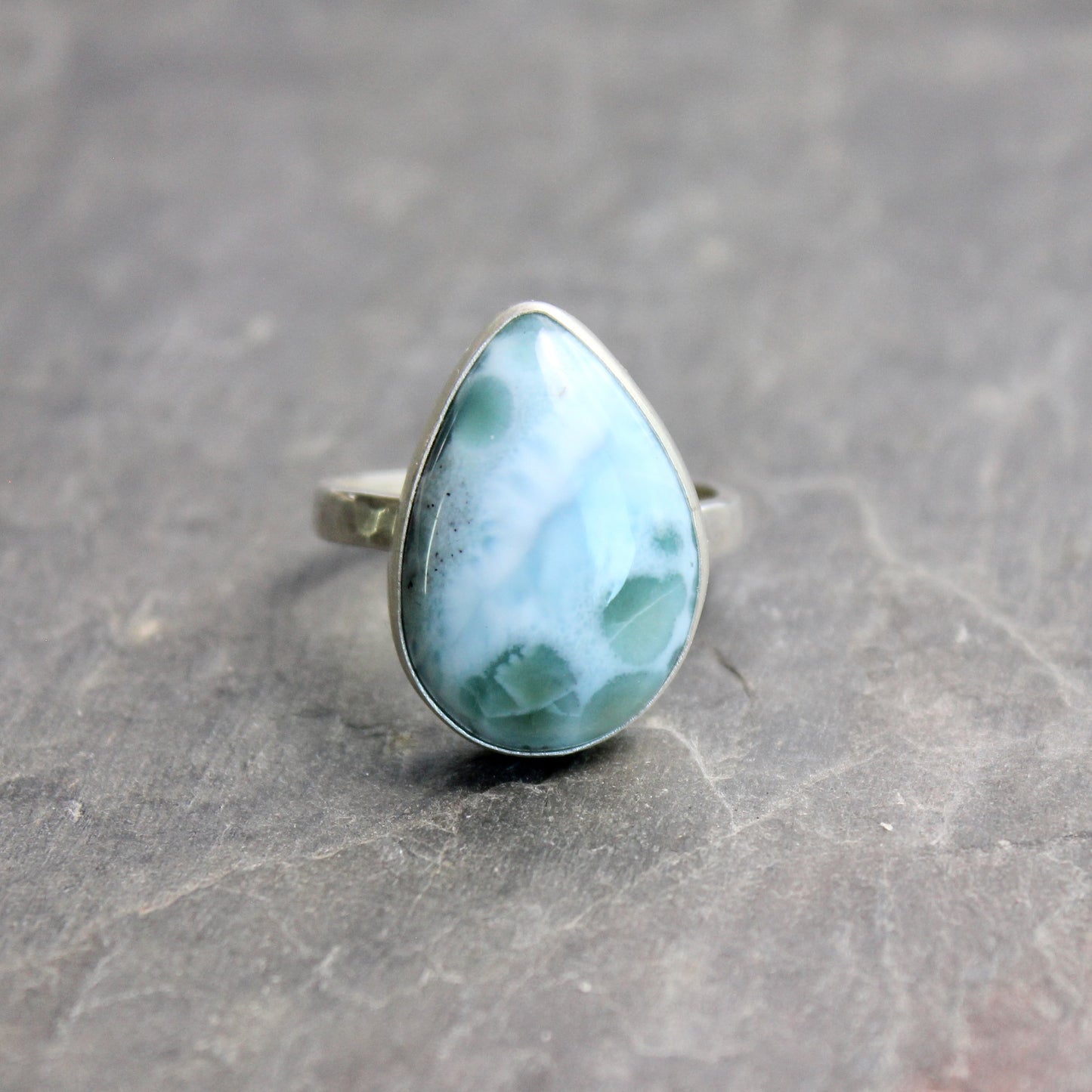 Teardrop-shaped larimar ring on a gray surface