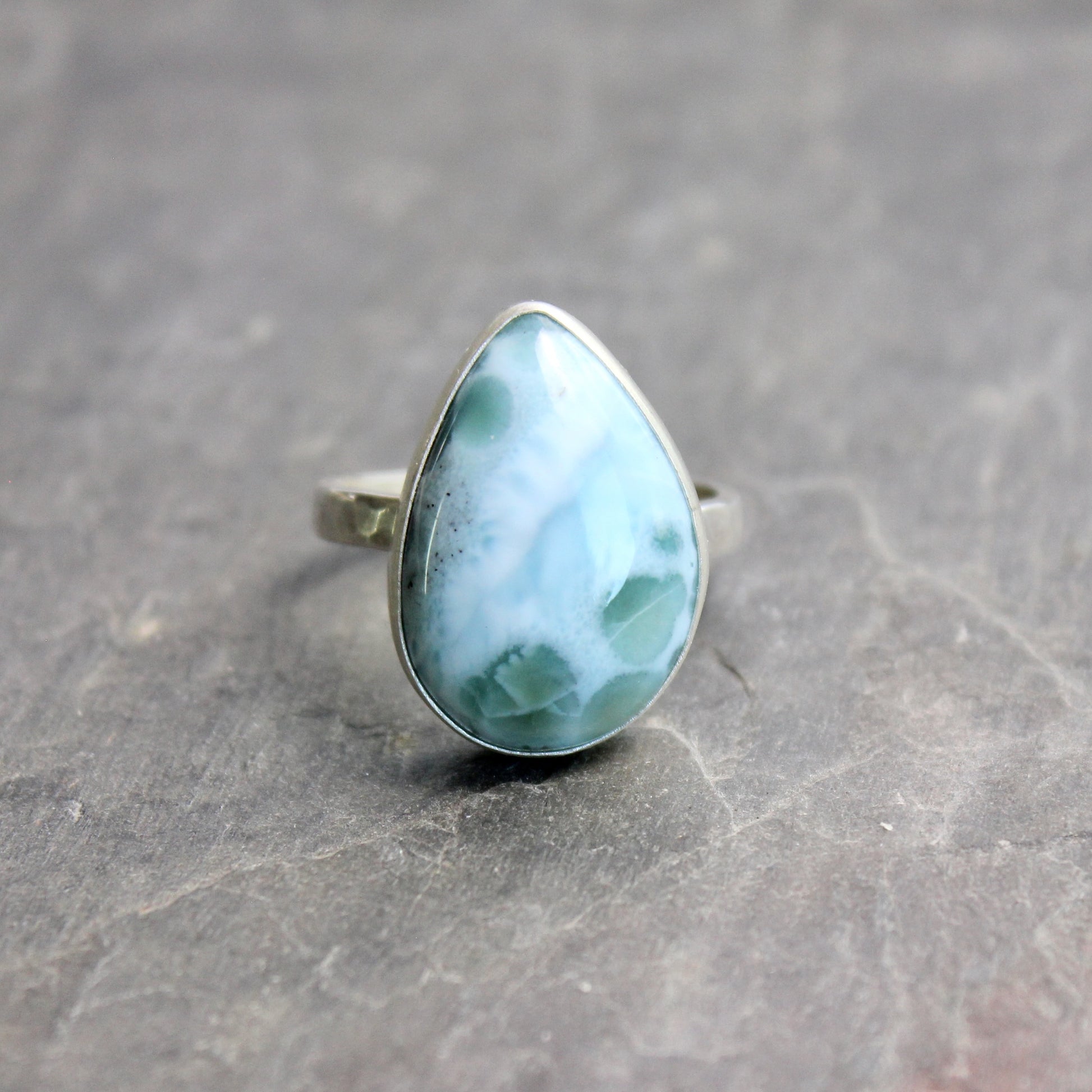 Teardrop-shaped larimar ring on a gray surface