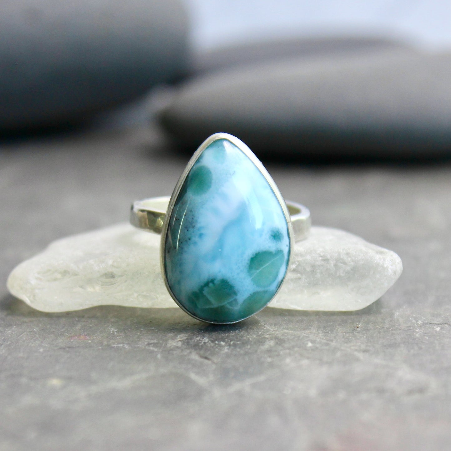 Teardrop-shaped larimar ring on a gray surface