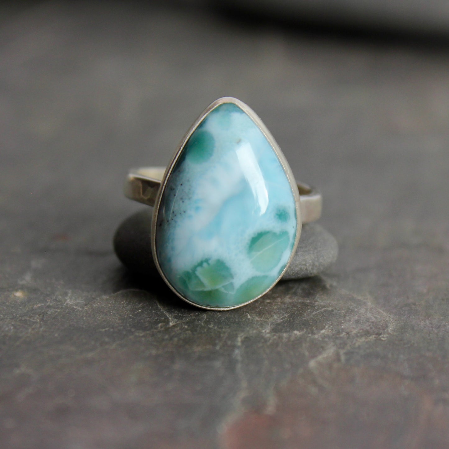 Teardrop-shaped larimar ring on a gray surface