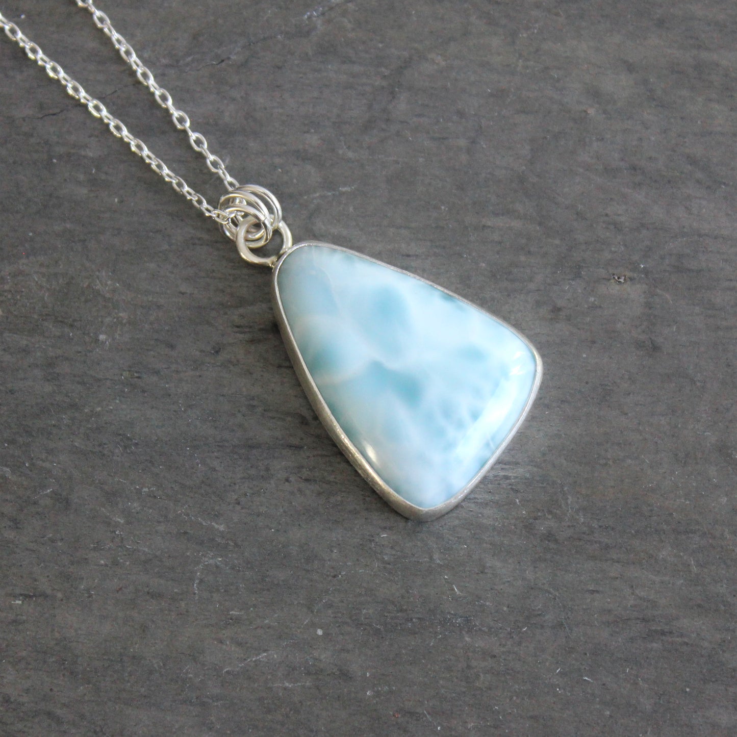 Necklace with a triangular blue larimar pendant on a dark gray background