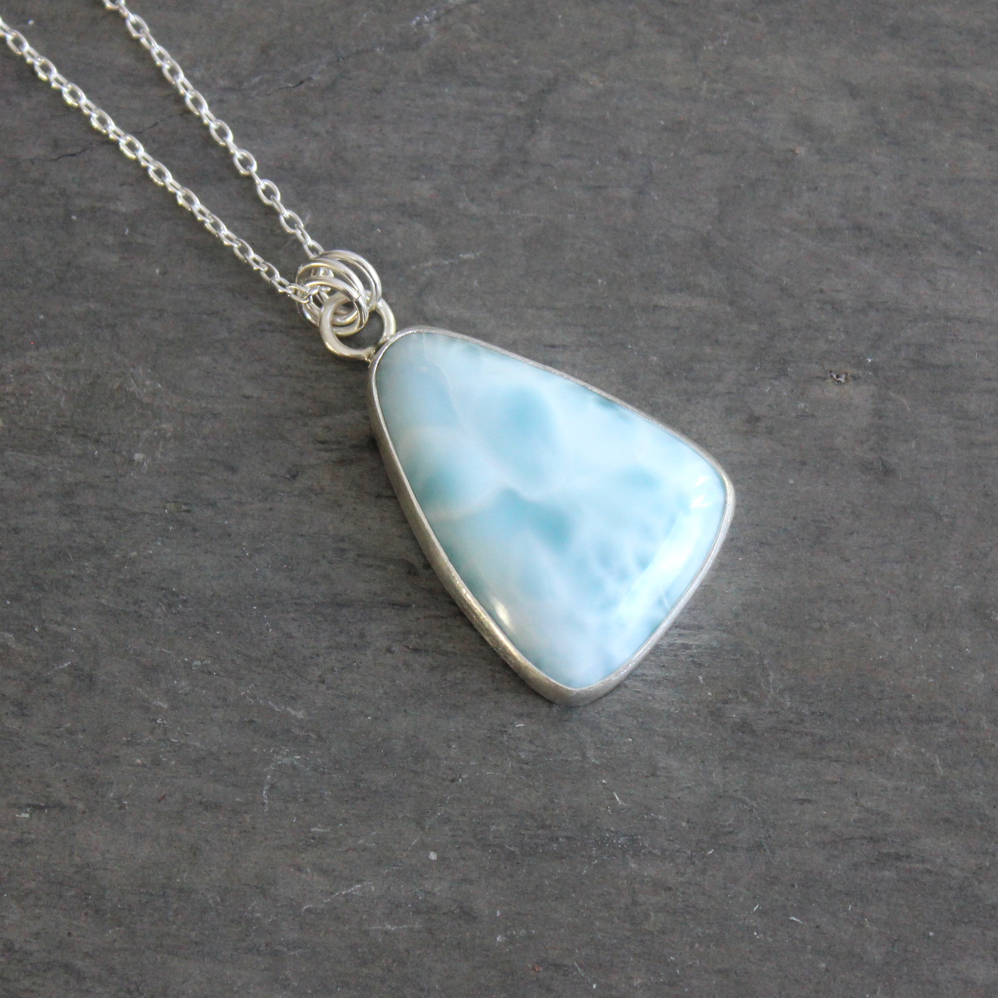 Necklace with a triangular blue larimar pendant on a dark gray background