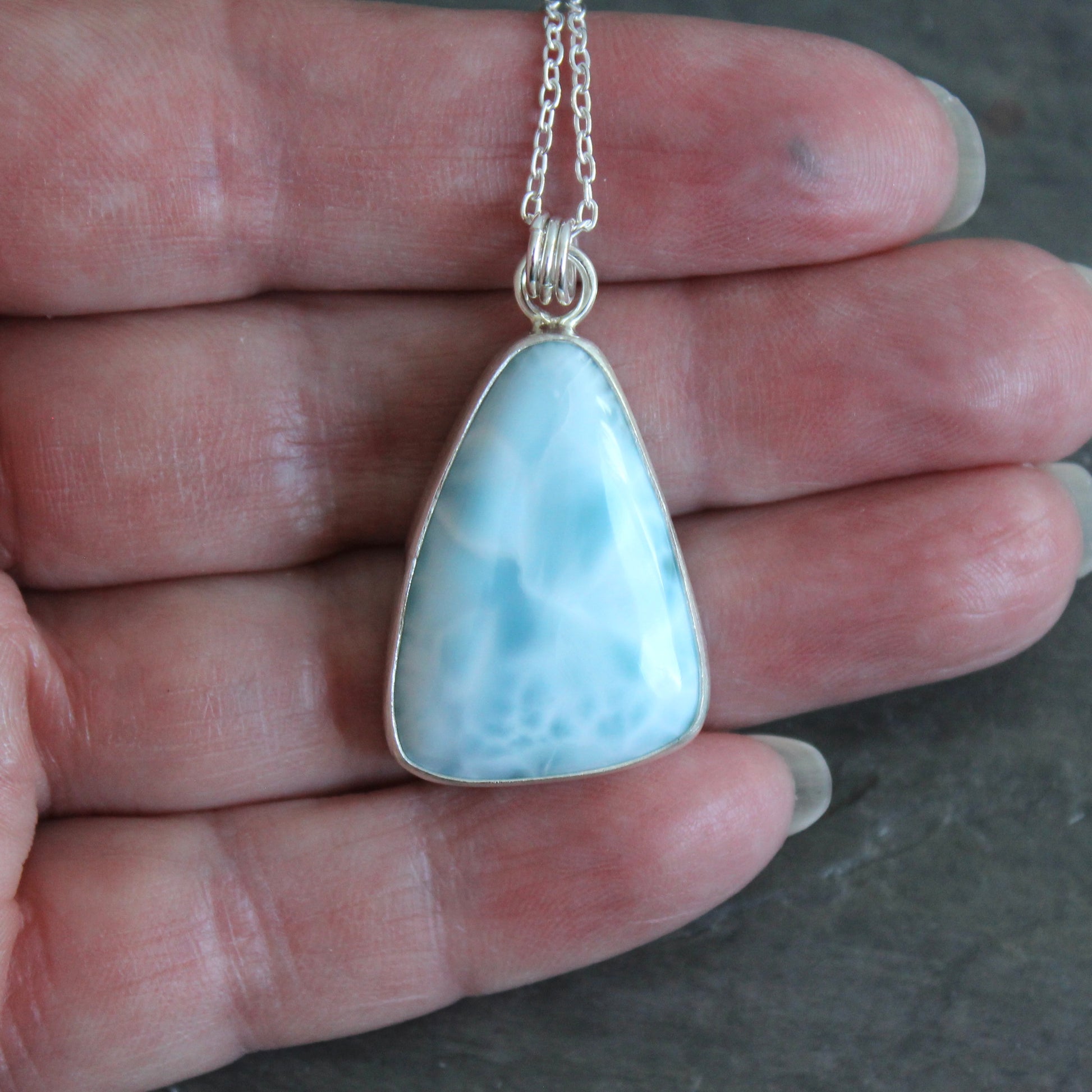 Necklace with a triangular blue larimar pendant on a dark gray background