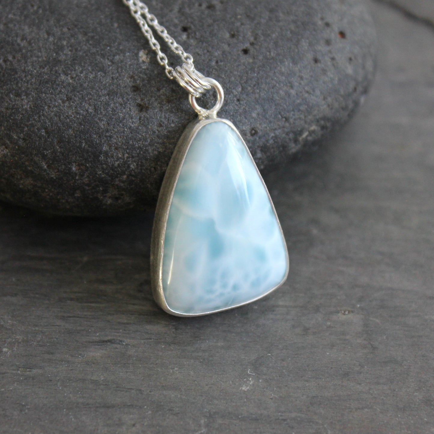 Necklace with a triangular blue larimar pendant on a dark gray background