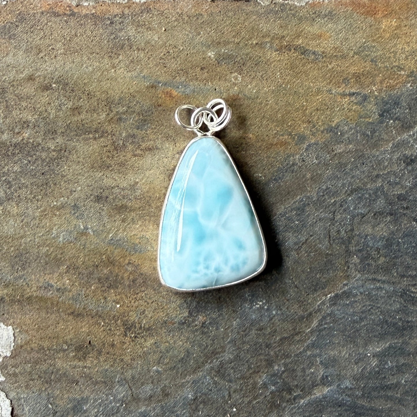 Necklace with a triangular blue larimar pendant on a dark gray background