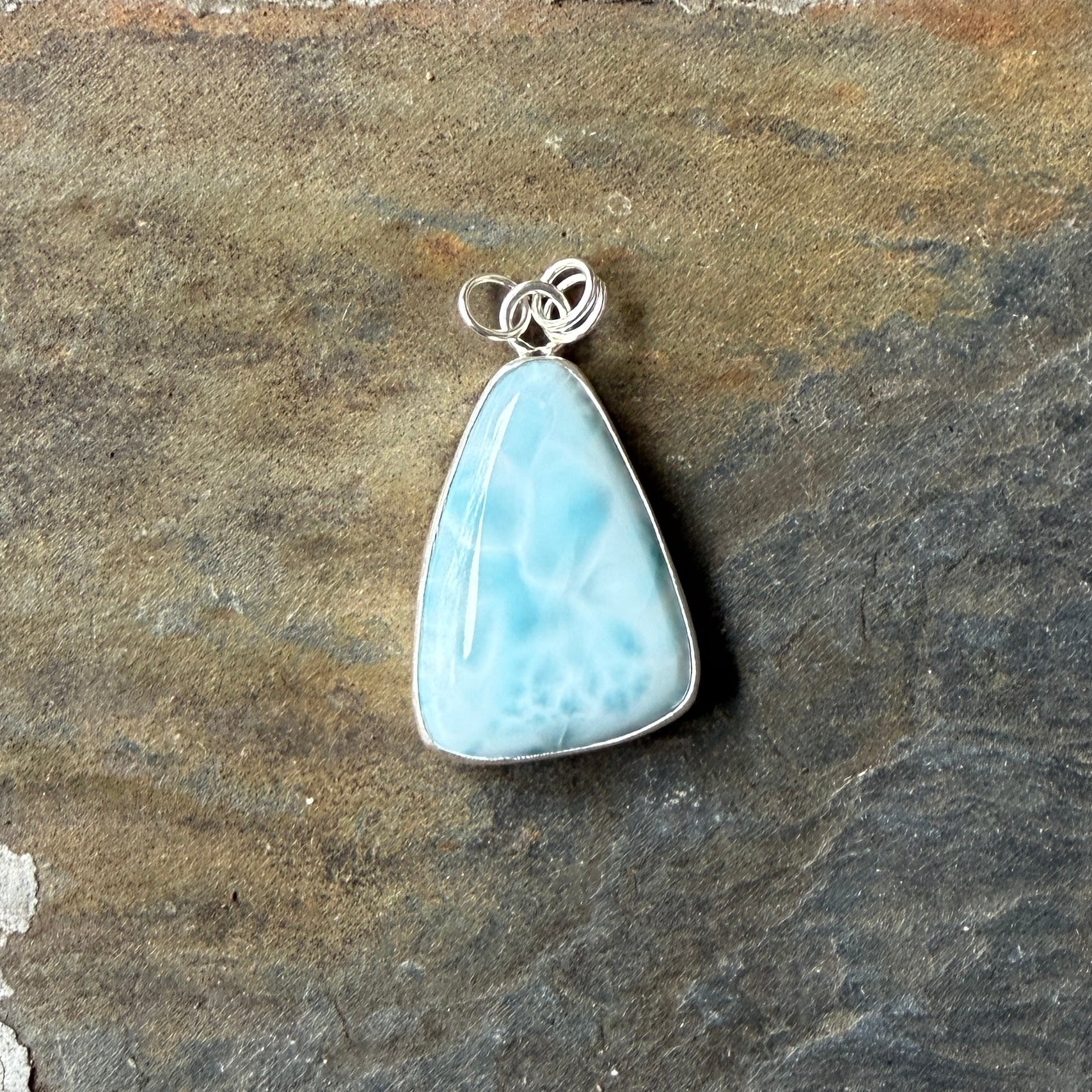 Necklace with a triangular blue larimar pendant on a dark gray background