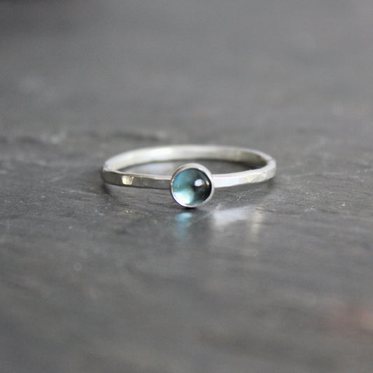 Silver ring with a london blue topaz on a dark gray surface