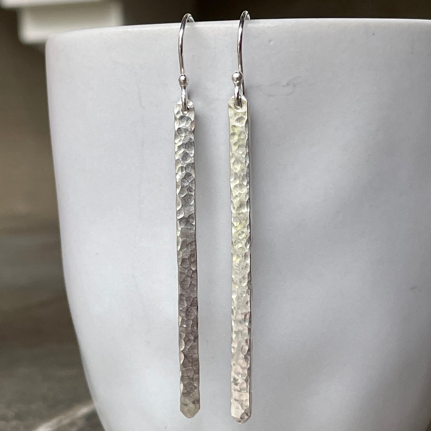 Pair of silver long earrings on a white surface