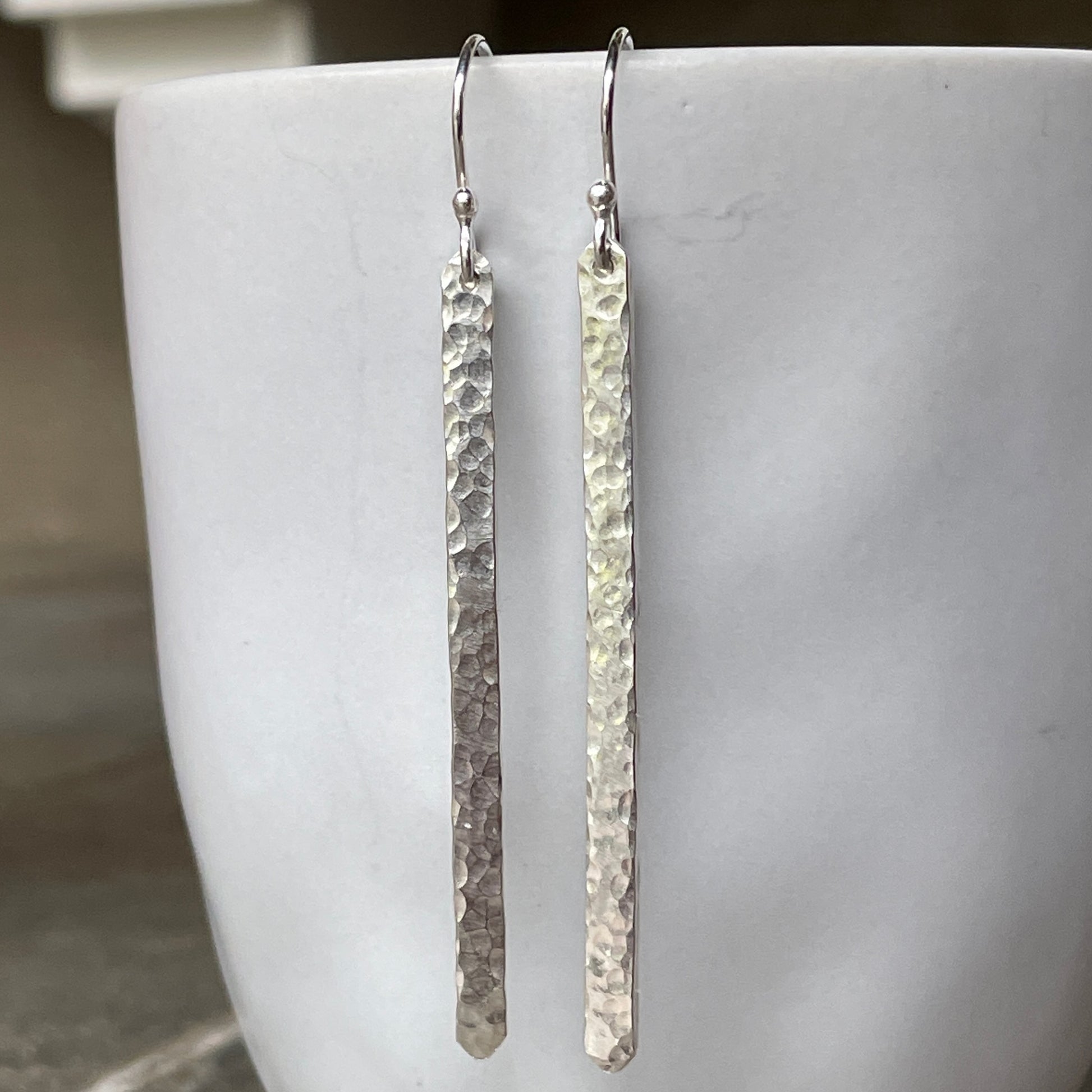 Pair of silver long earrings on a white surface