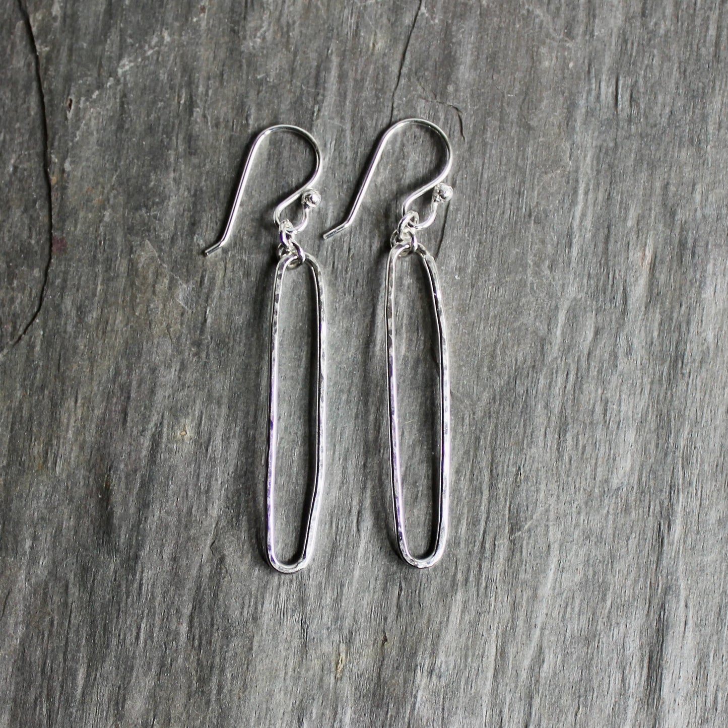 Pair of sterling silver oval earrings on a gray surface