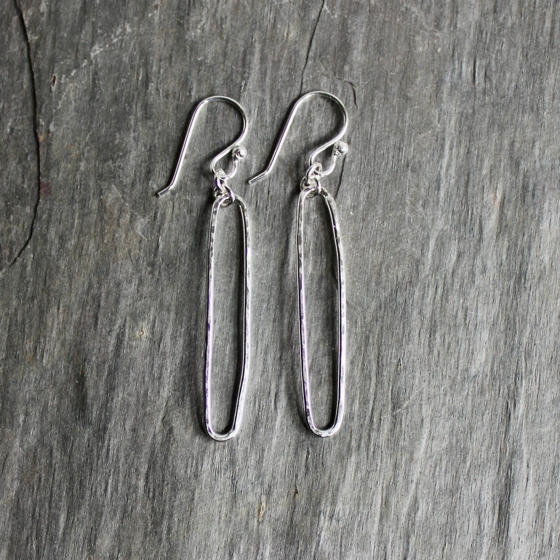 Pair of sterling silver oval earrings on a gray surface