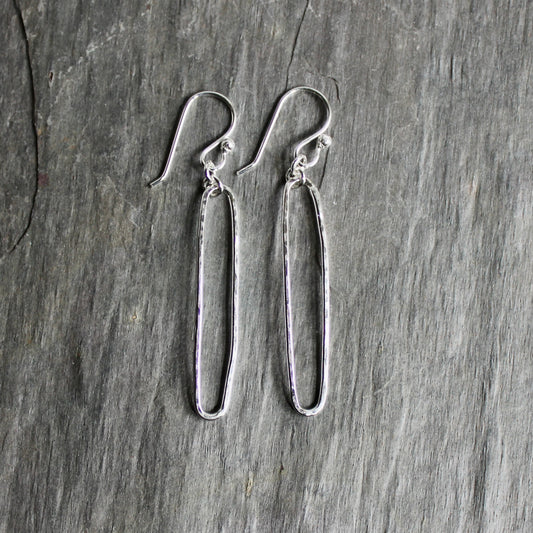Pair of sterling silver oval earrings on a gray surface