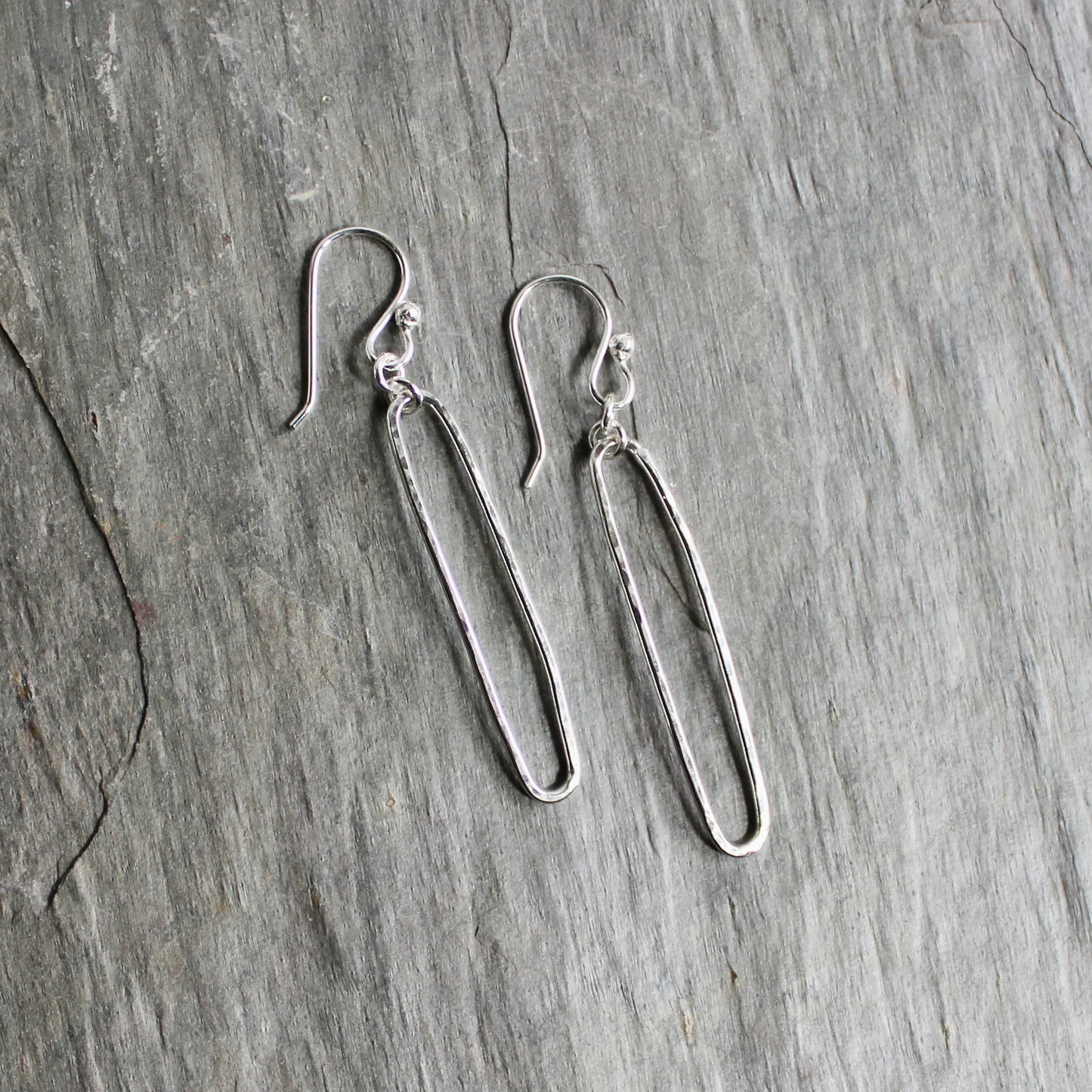 Pair of sterling silver oval earrings on a gray surface