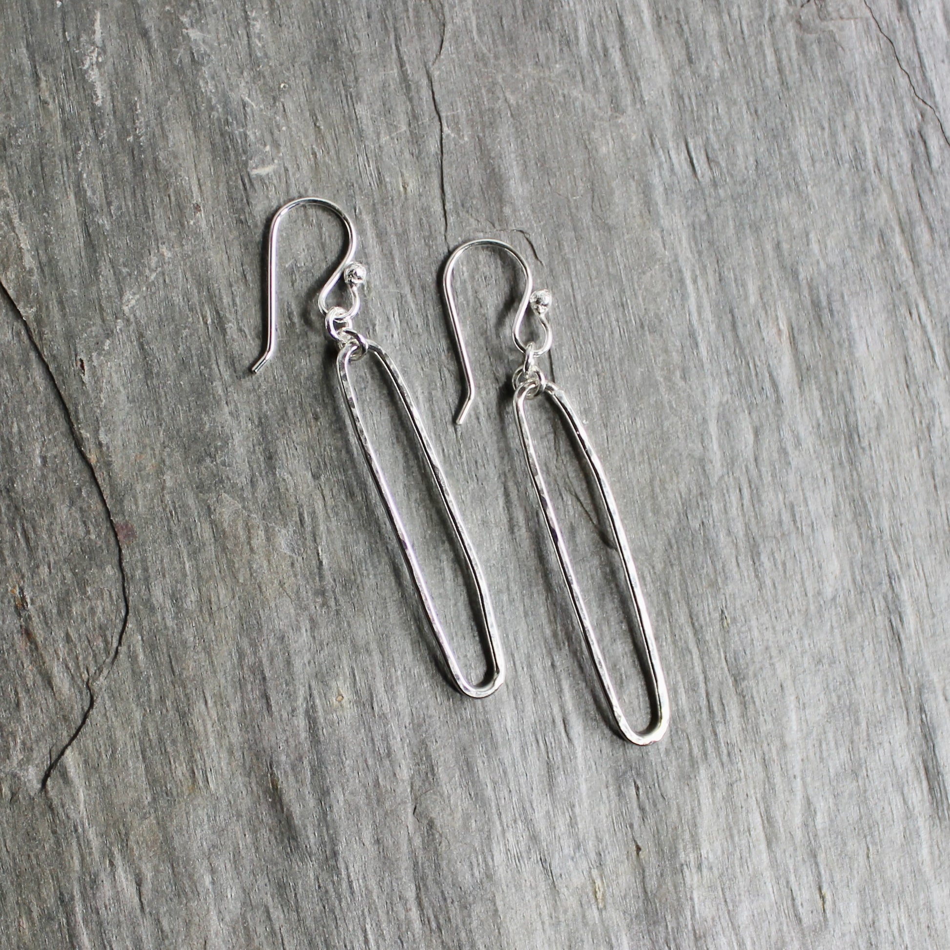 Pair of sterling silver oval earrings on a gray surface