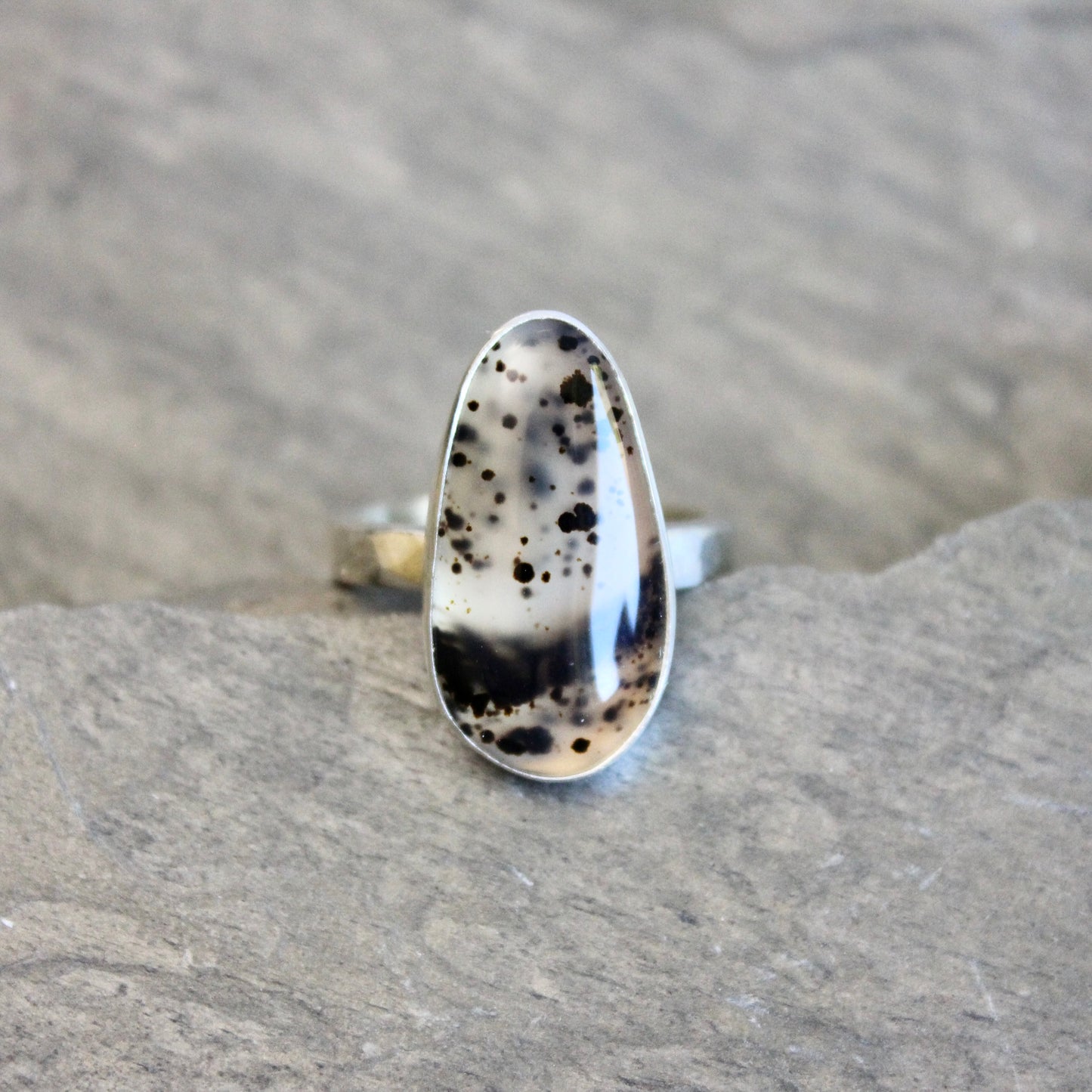 Silver ring with a Spotted Montana agate on a gray rock background