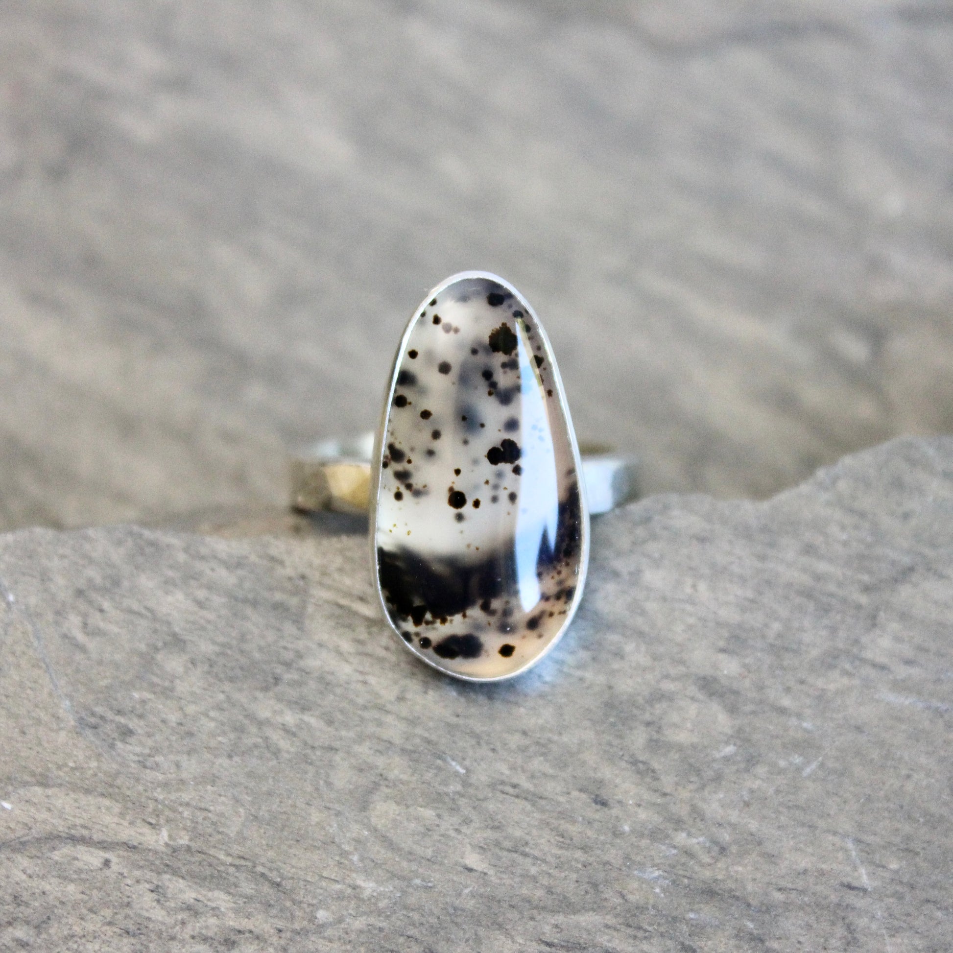 Silver ring with a Spotted Montana agate on a gray rock background