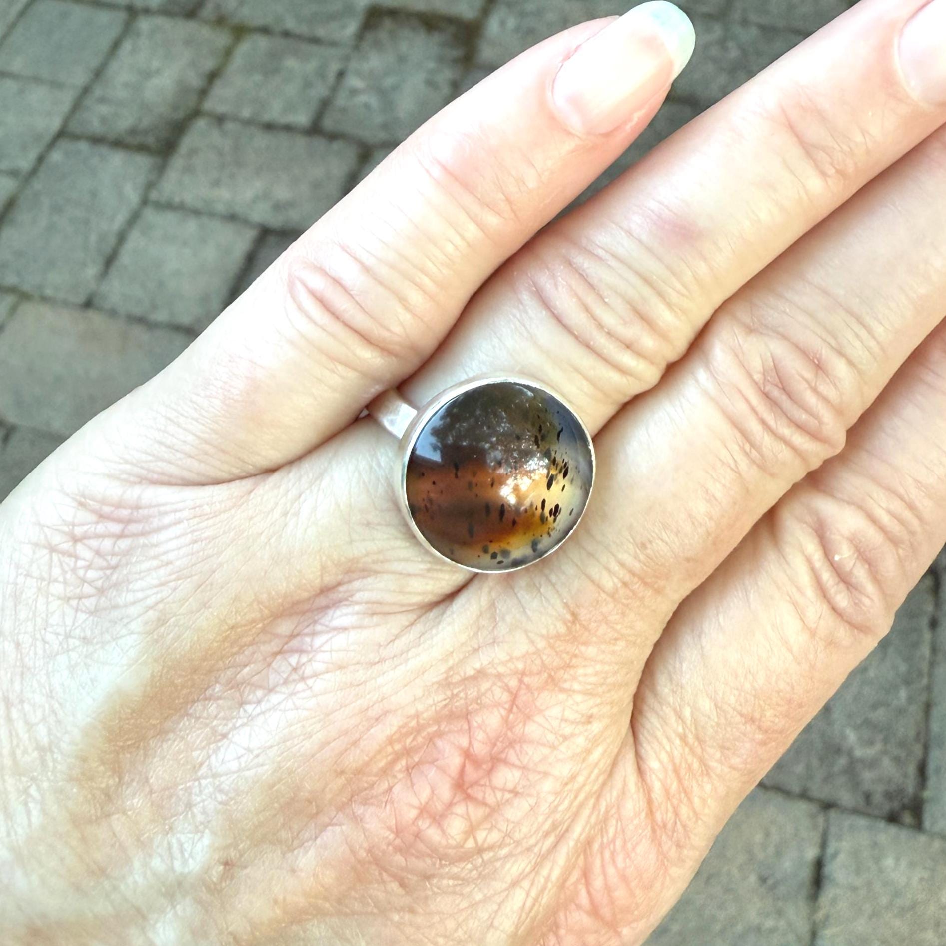 This pretty ring has a splotchy round Montana agate cabochon set in a fine and sterling silver bezel setting on a sturdy hammered band. Handmade by Will Macy in Corvallis, OR. Size 8 1/2