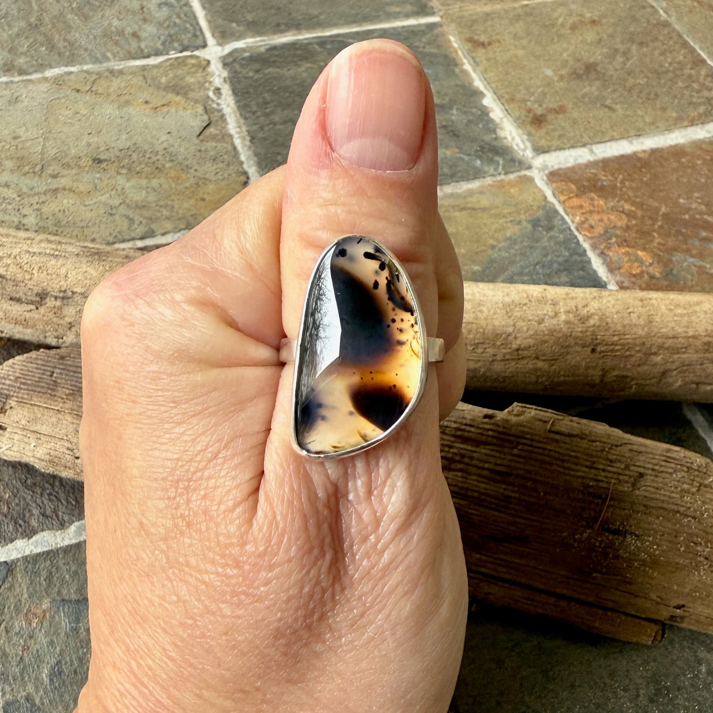 Hand wearing a ring with a large montana agate