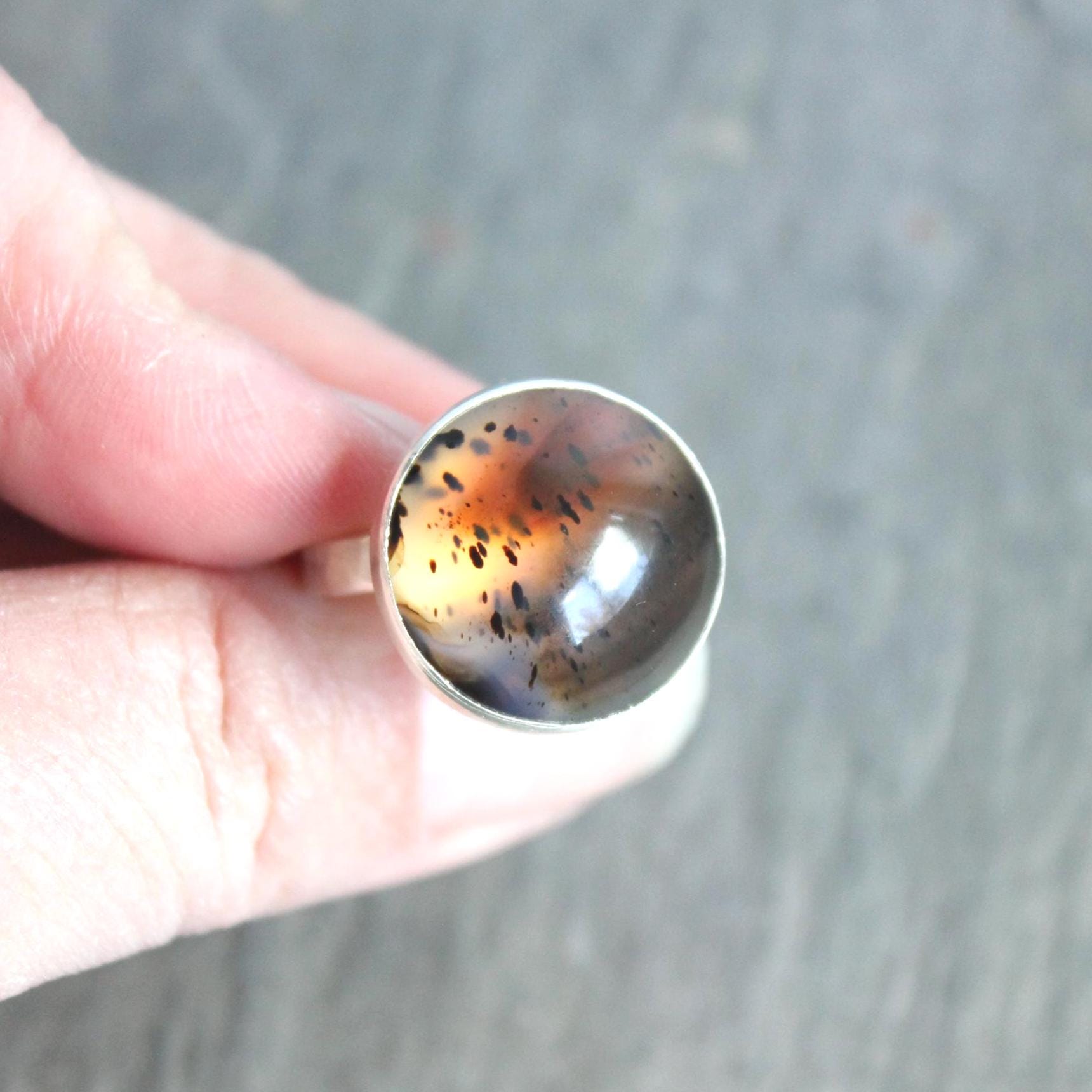 This pretty ring has a splotchy round Montana agate cabochon set in a fine and sterling silver bezel setting on a sturdy hammered band. Handmade by Will Macy in Corvallis, OR. Size 8 1/2