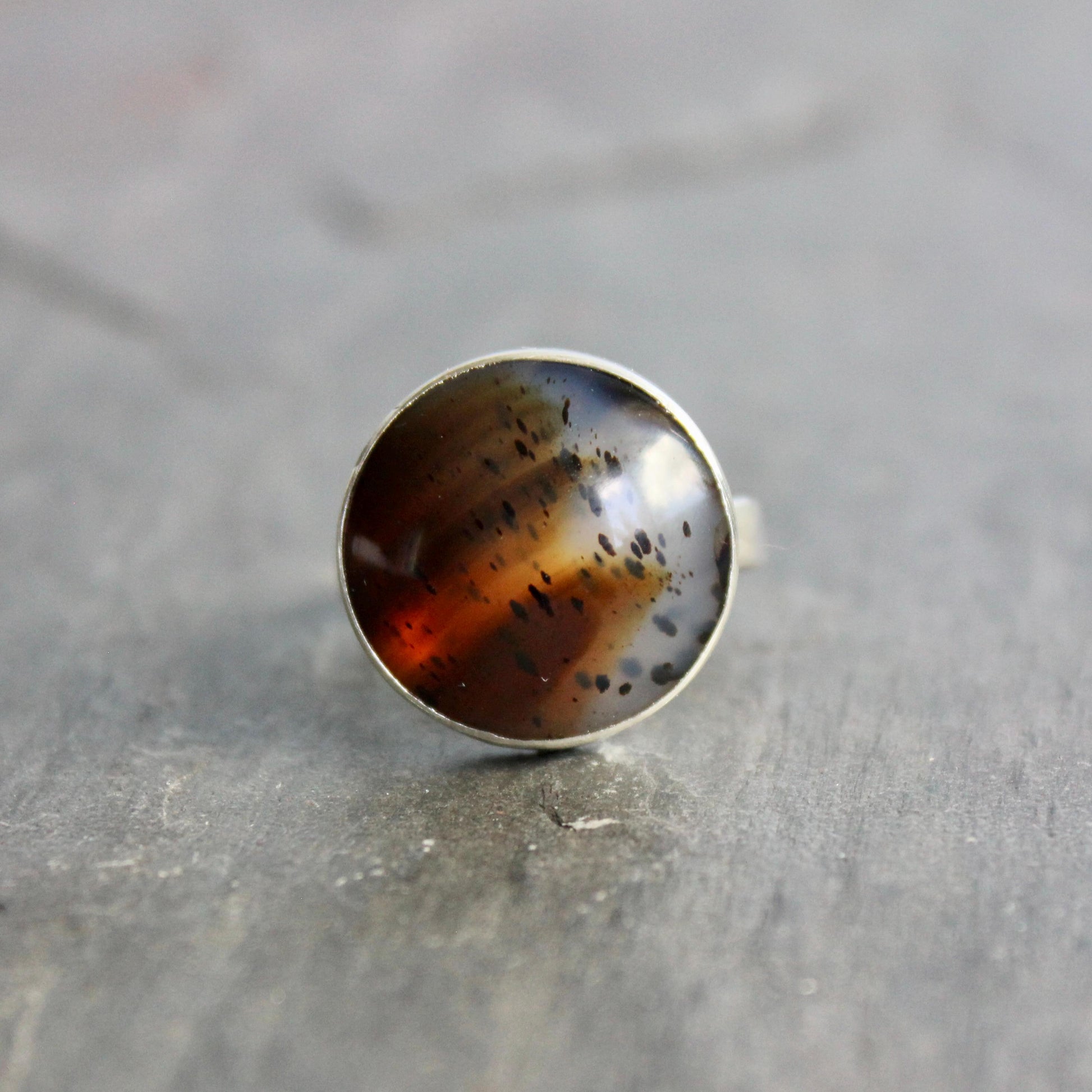 This pretty ring has a splotchy round Montana agate cabochon set in a fine and sterling silver bezel setting on a sturdy hammered band. Handmade by Will Macy in Corvallis, OR. Size 8 1/2